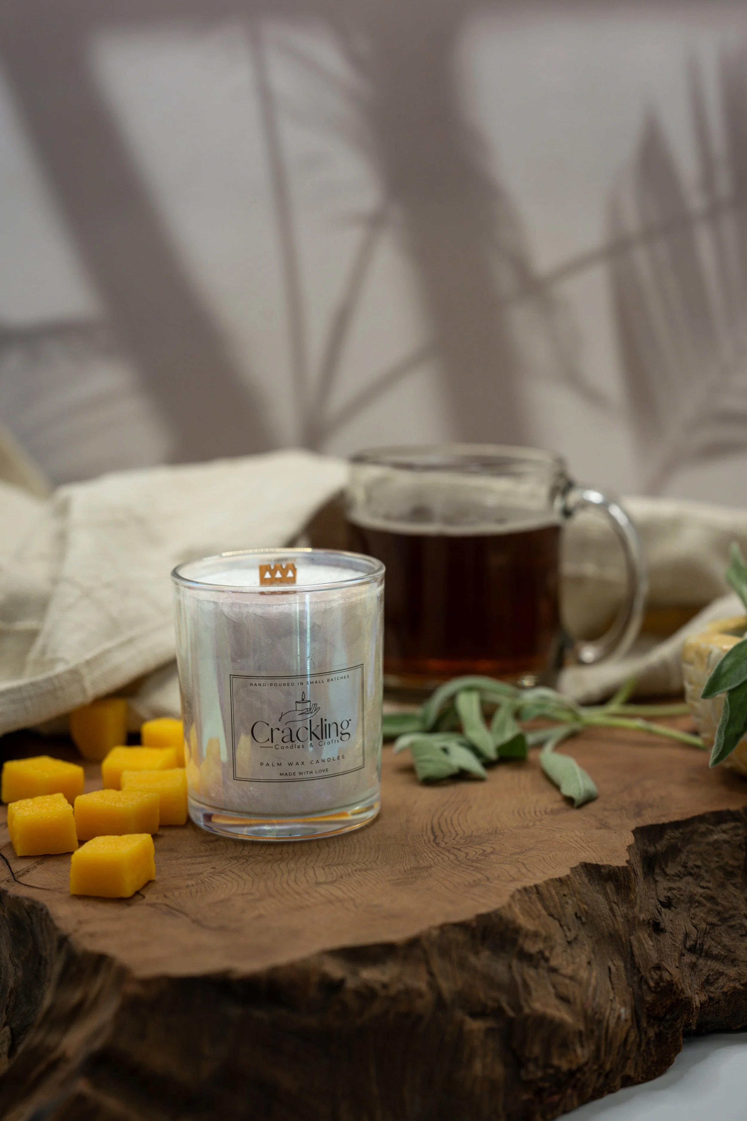 Mango Papaya palm wax candle on a live edge wooden board with mango cubes, a glass mug, and greenery.