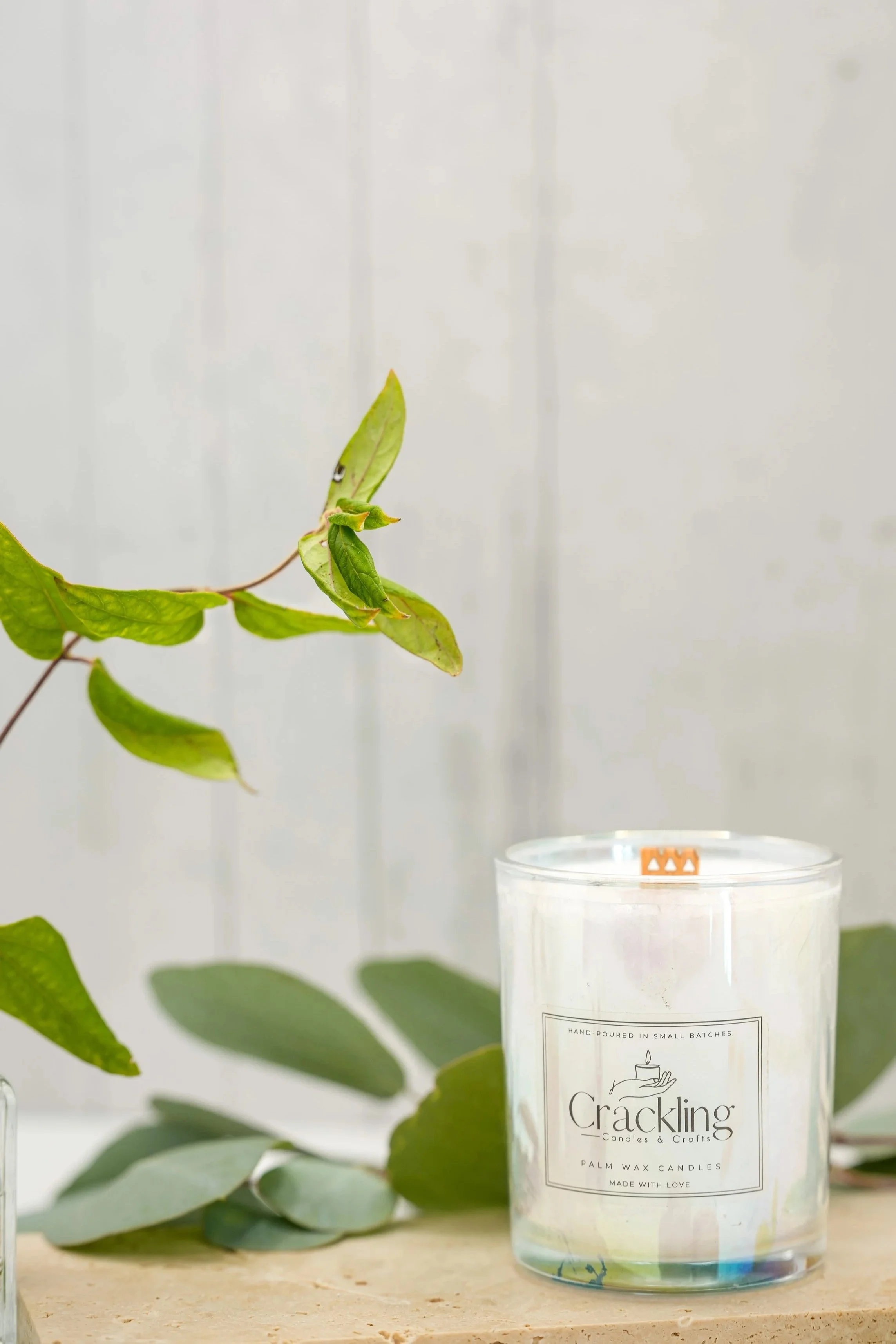 Eucalyptus & Spearmint candle displayed on a beige stone riser with eucalyptus greenery and smooth stones against a neutral background.