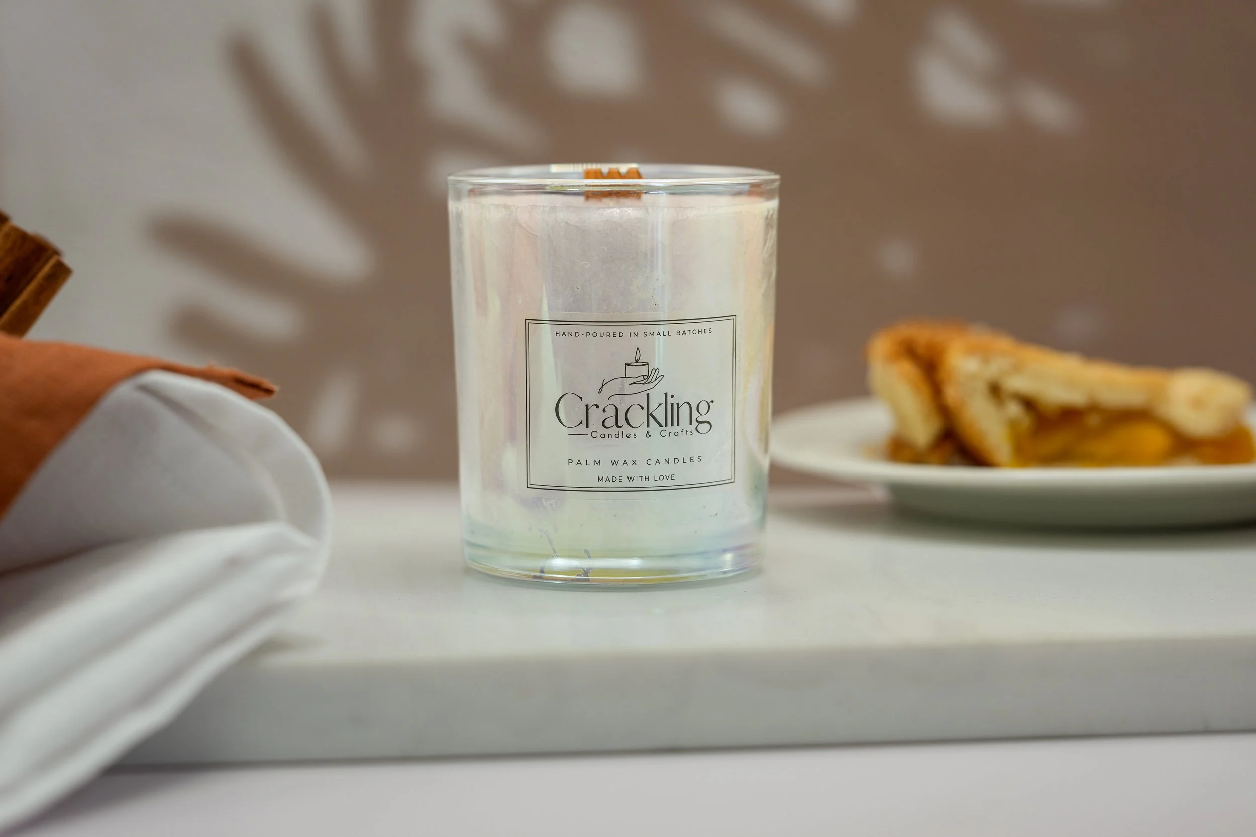 Close view of the Hot Baked Apple Pie candle with its wooden wick and apple pie in the background