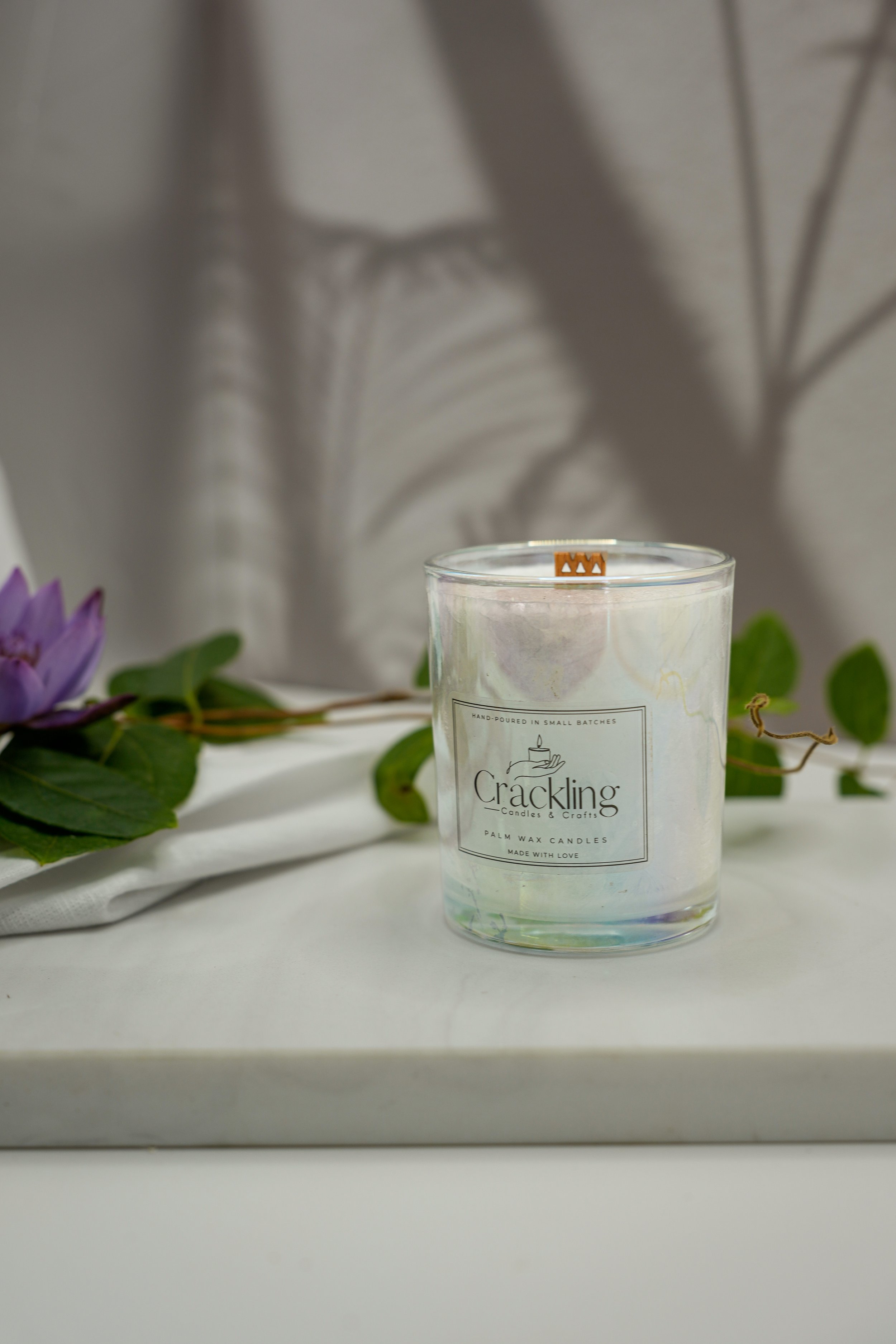 Close front view of a Water Lily & Jasmine candle with a wooden wick and purple flower