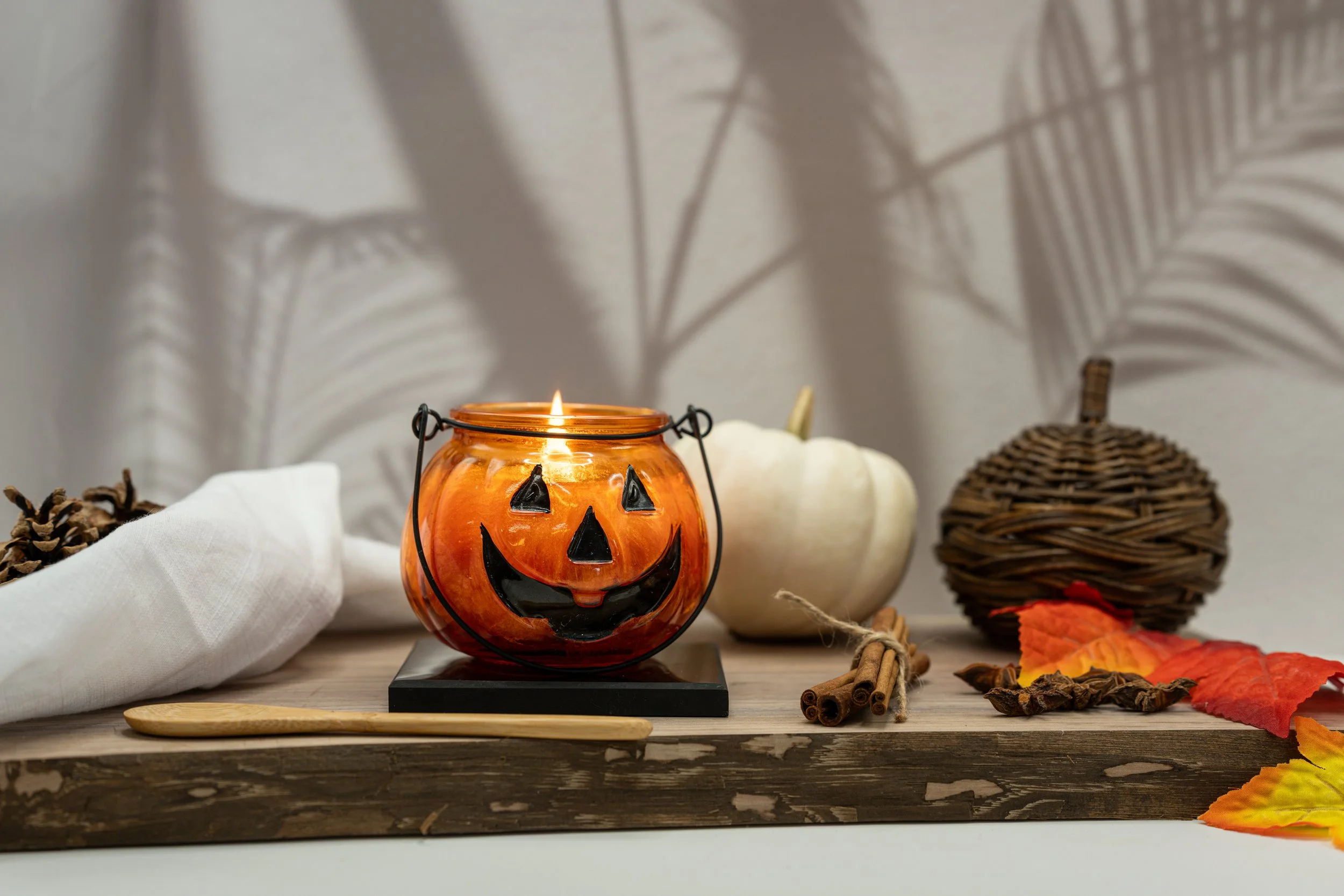 Hand-poured Pumpkin Spice Glass Pumpkin Candle with a wooden wick, styled with white pumpkins and warm autumn accents.
