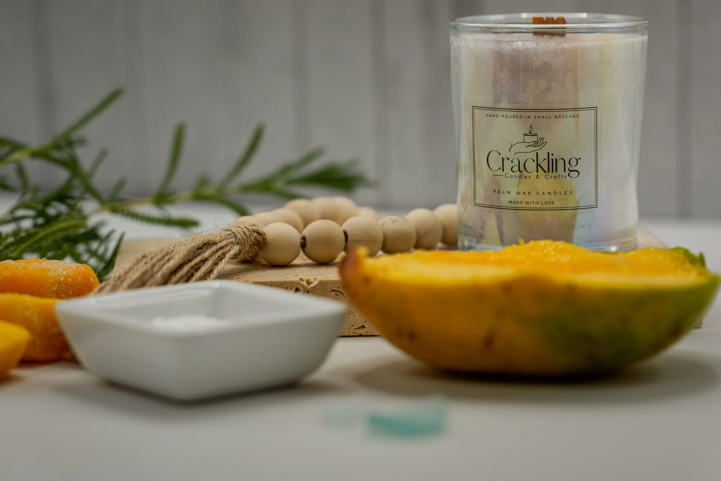 Mango Papaya candle styled with a papaya half, a small white bowl, wooden beads, and greenery.