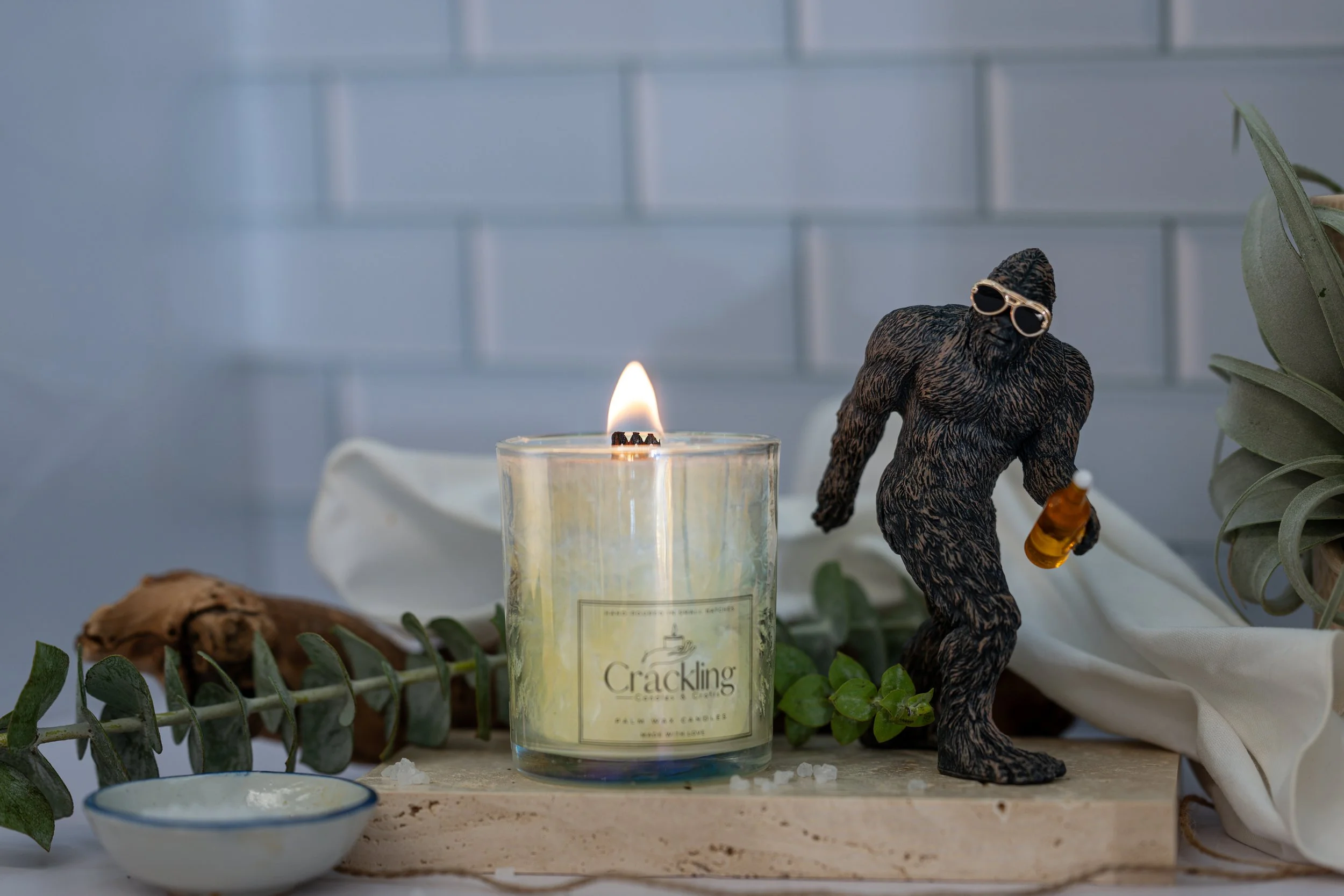 Lit White Sage & Sea Salt candle styled on a light wood board