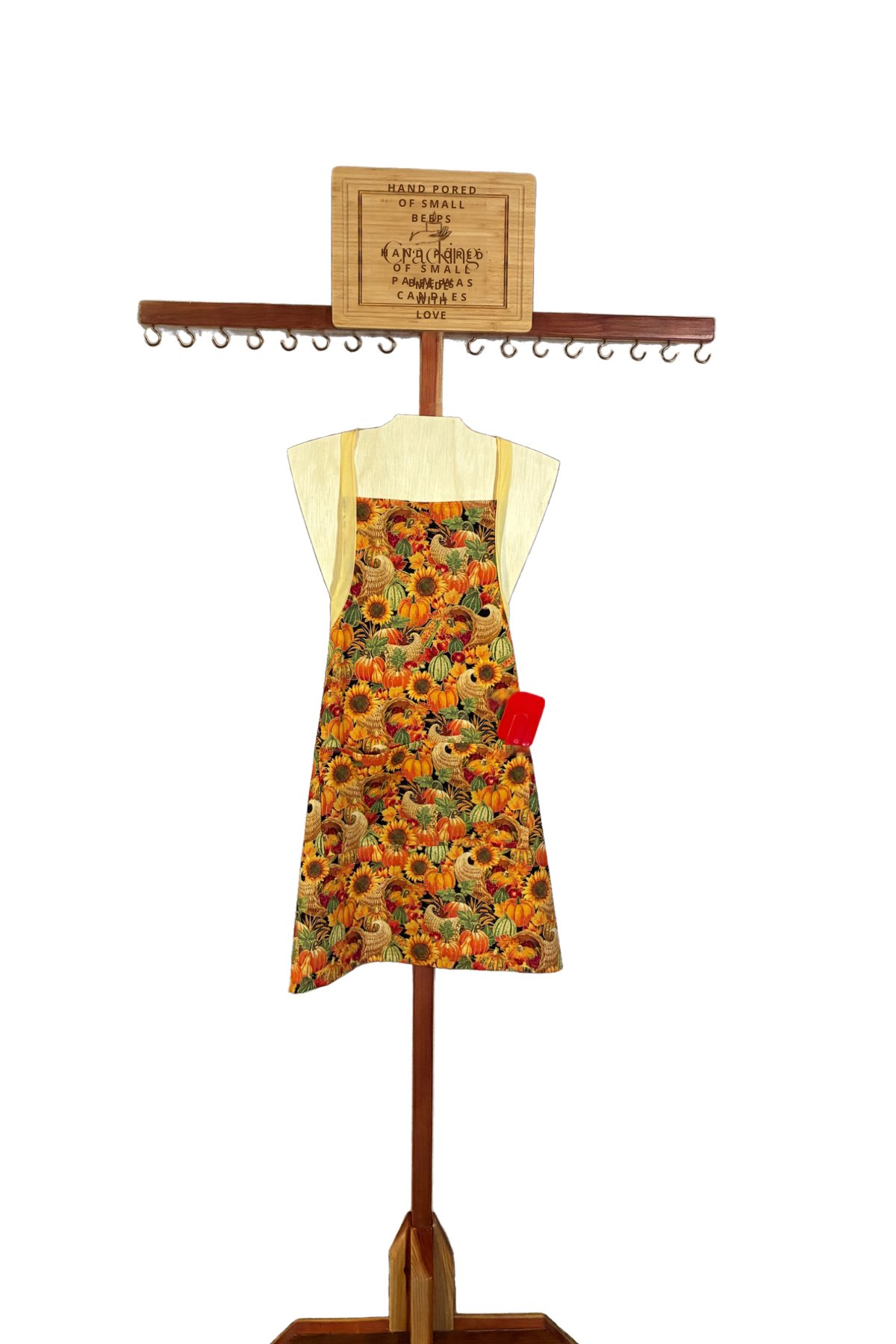 Handmade adult harvest apron with pumpkins, sunflowers, and cornucopias on a wooden display stand.