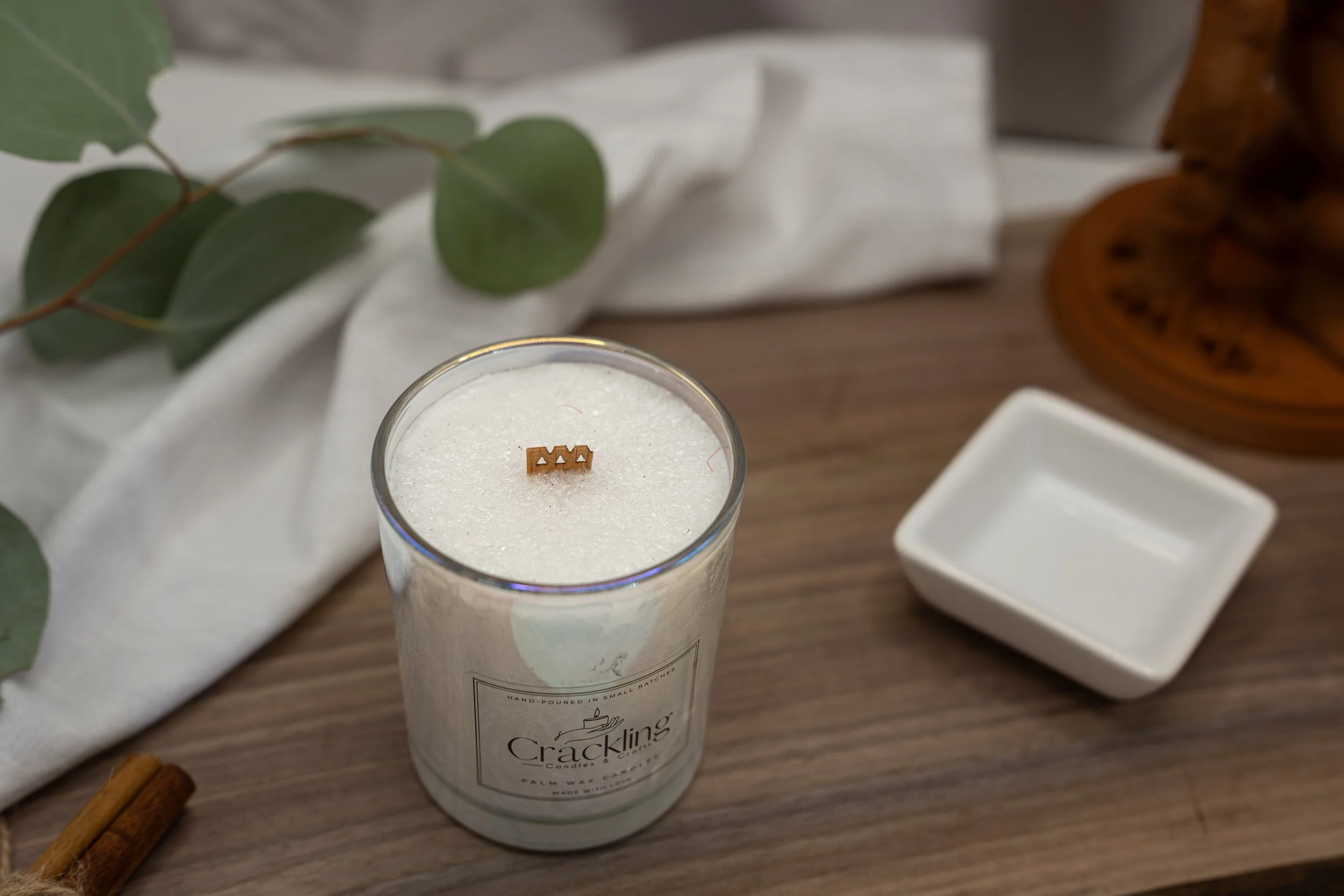 Top view of a handcrafted Coffee & Whiskey palm wax candle with a wooden wick on a warm wood surface.