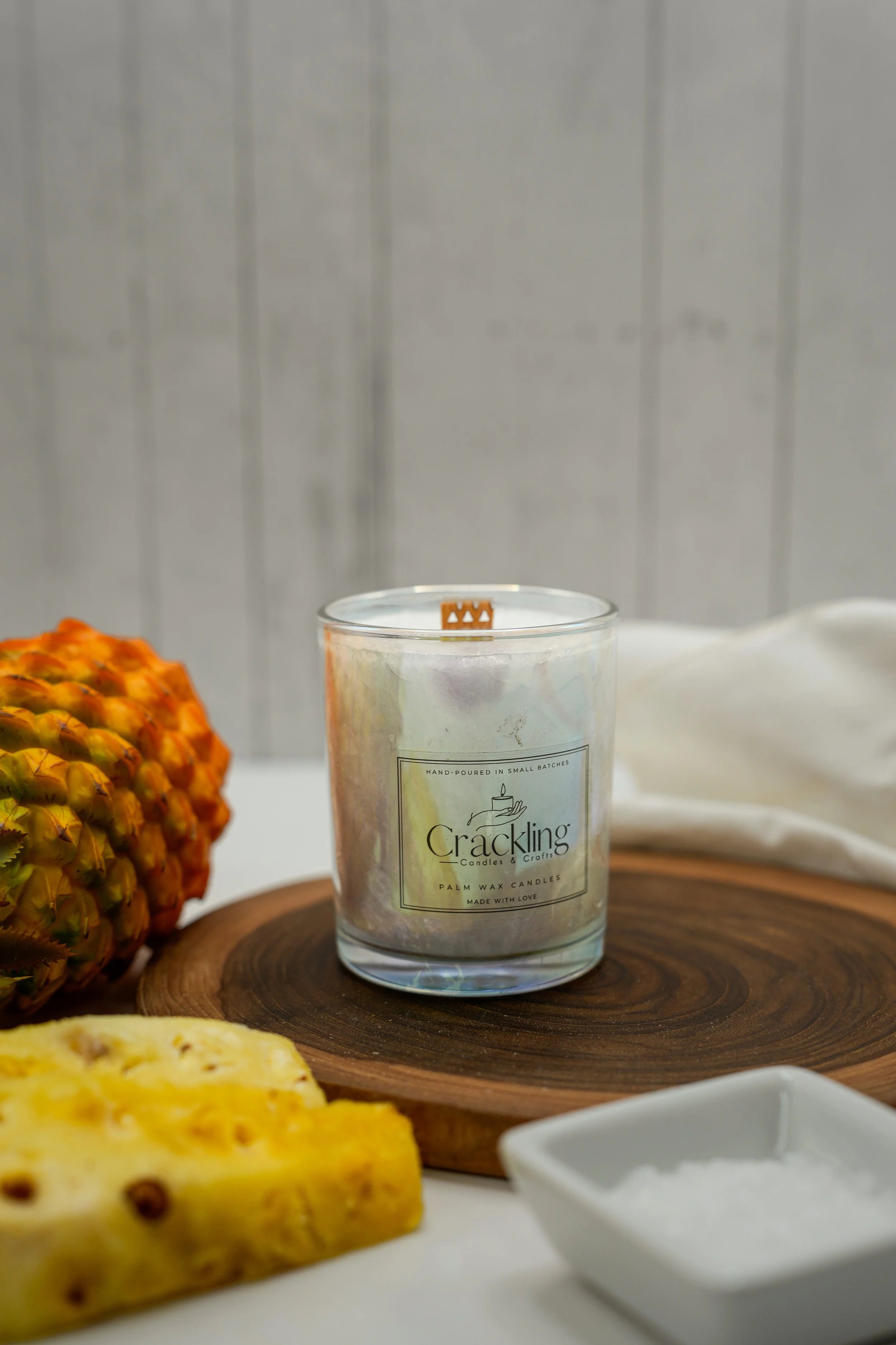 6 oz Iced Pineapple palm wax candle on a wooden board beside fresh pineapple