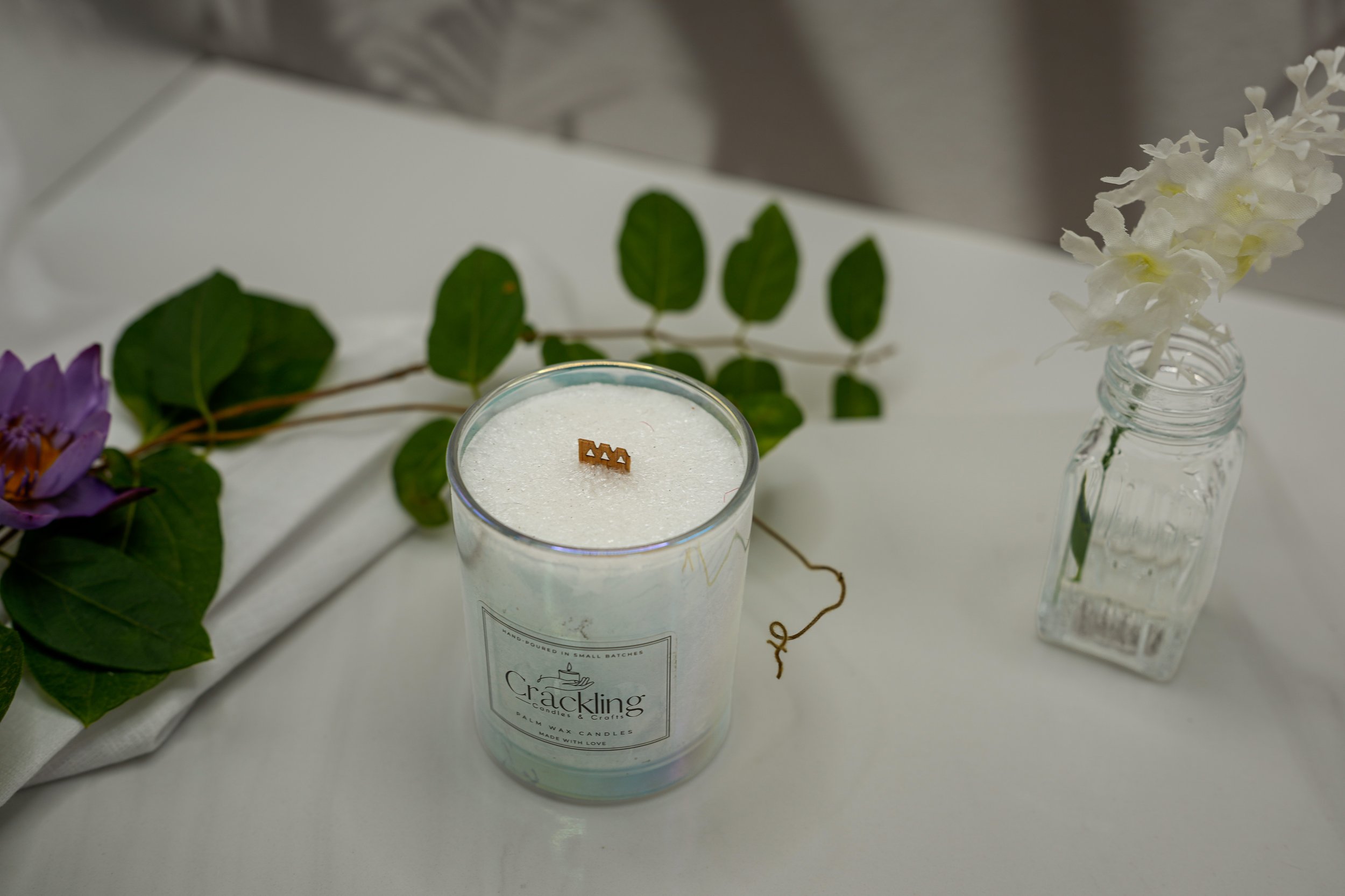 Top view of a 6 oz Water Lily & Jasmine palm wax candle with a wooden wick and green leaves