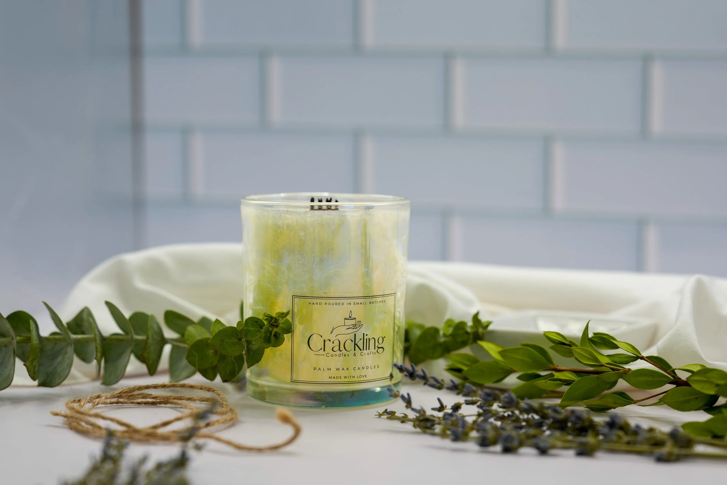 Hand-poured Honeysuckle candle in iridescent glass with greenery and soft white fabric