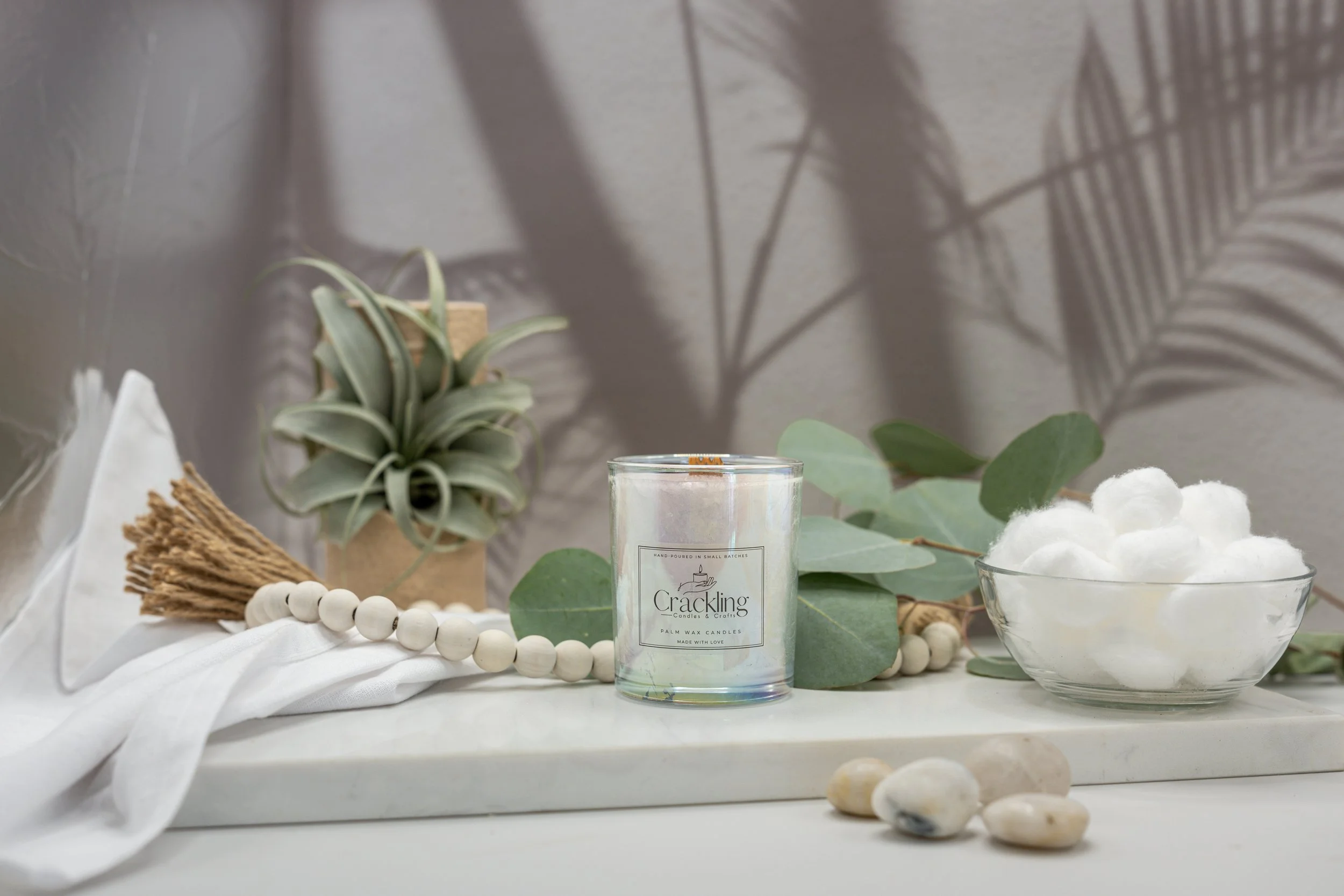 6 oz Baby Powder palm wax candle with a wooden wick, styled with eucalyptus, white cotton, natural beads, and soft greenery.