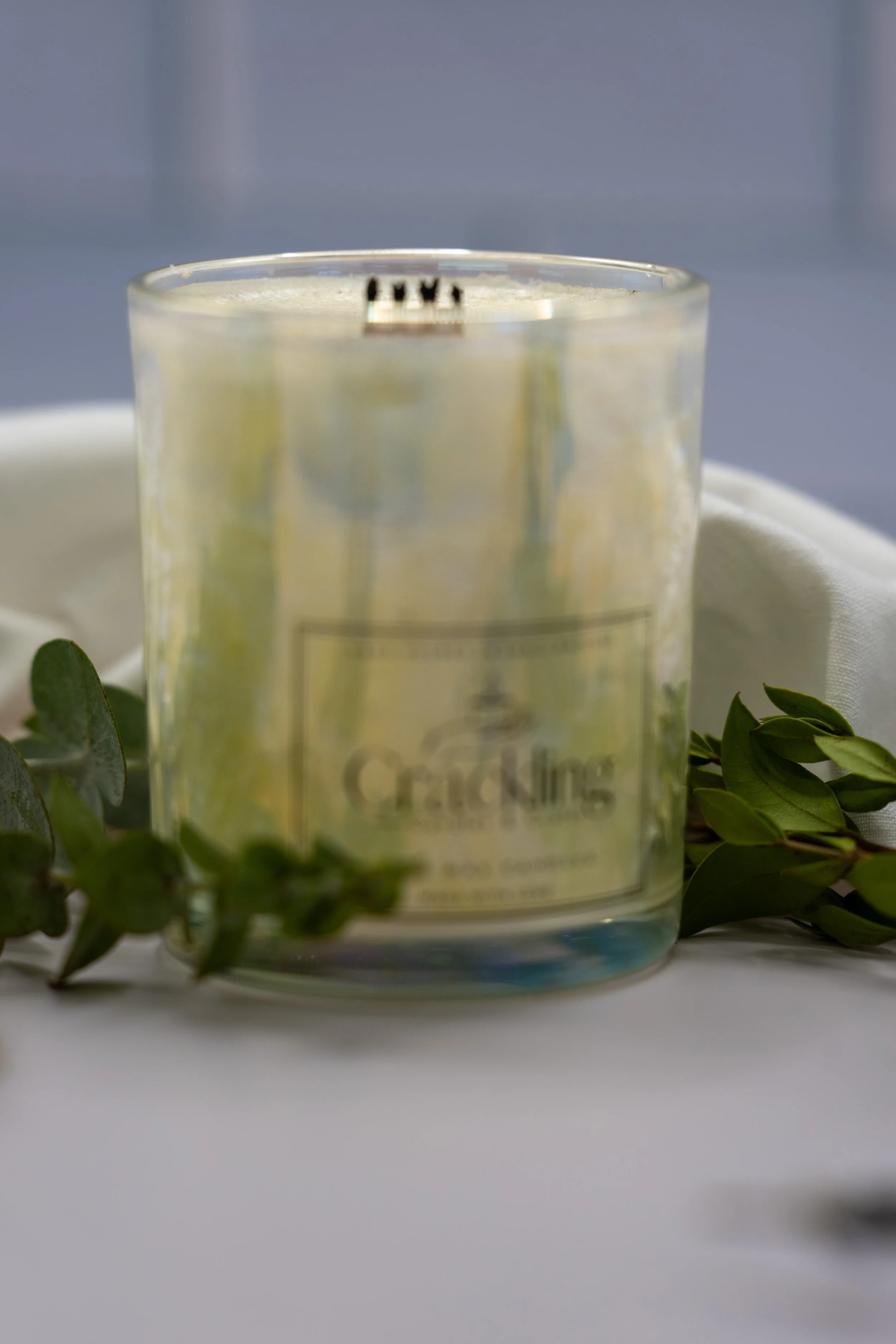6 oz Honeysuckle iridescent palm wax candle with a wooden wick, styled with greenery