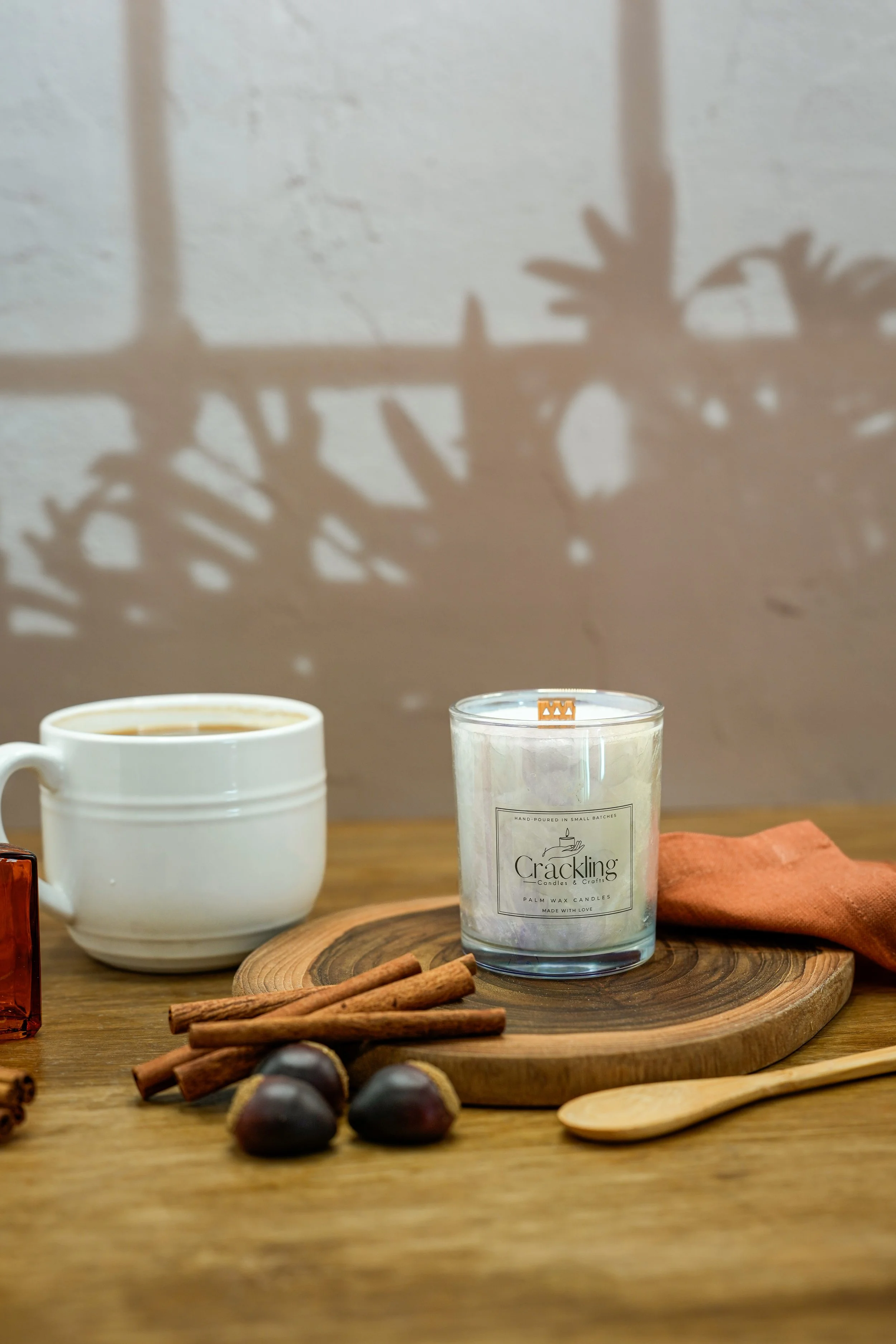 Hazelnut Cappuccino candle with a coffee cup, cinnamon sticks, and hazelnuts in a warm coffee-inspired setting