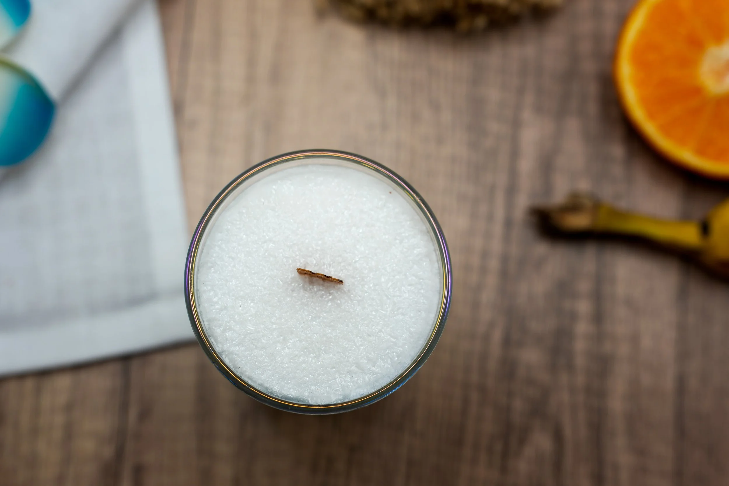 Top view of a 6 oz Café de Olla palm wax candle with a wooden wick on a warm natural wood surface.