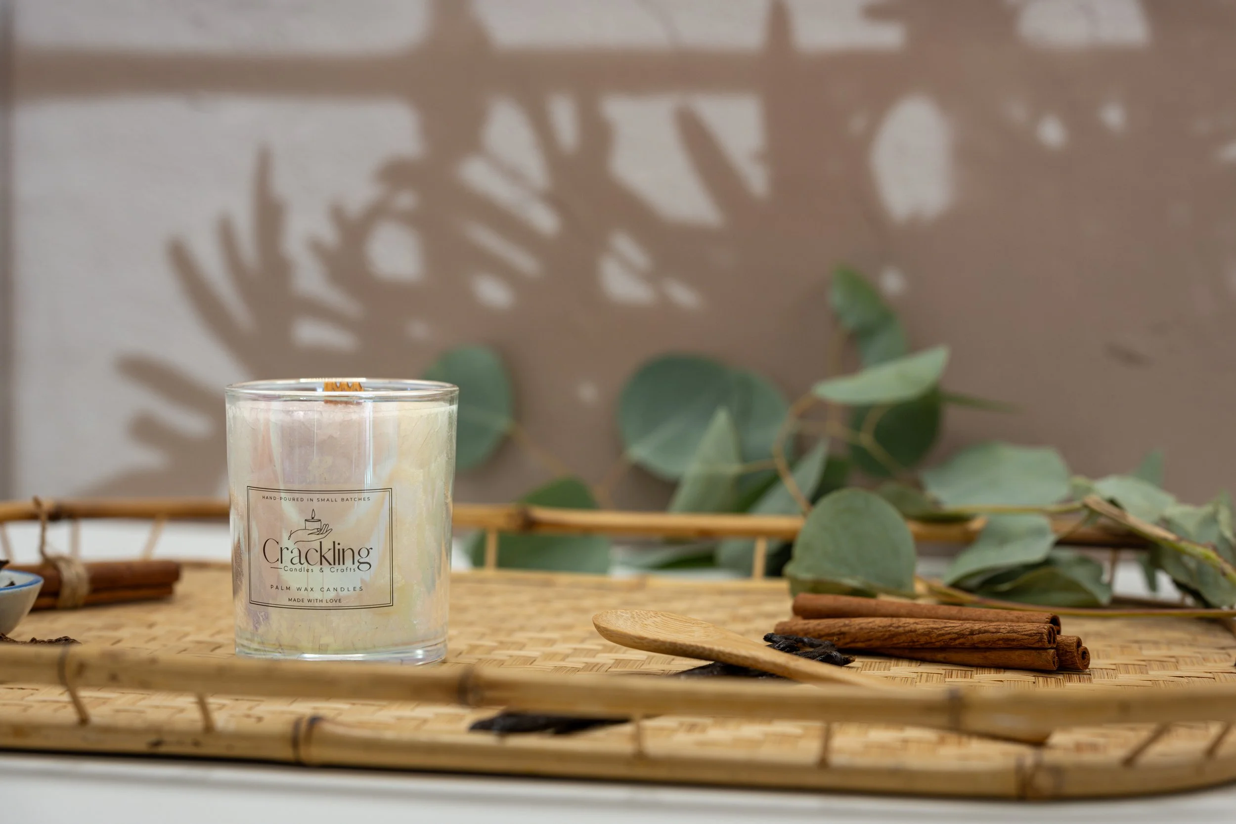 Cinnamon candle styled on a natural wood tray with eucalyptus leaves, cinnamon sticks, and warm rustic decor.