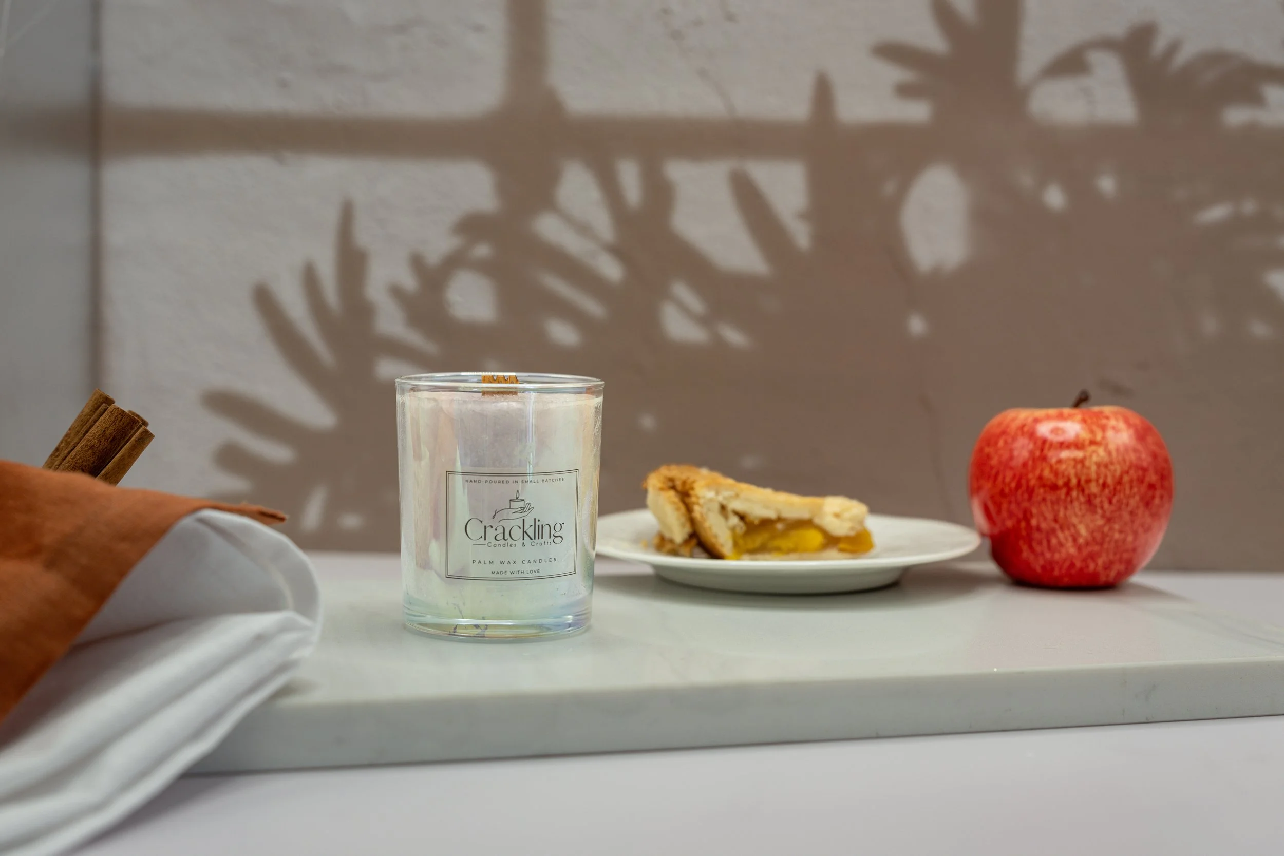 Hot Baked Apple Pie candle beside a slice of pie and a red apple