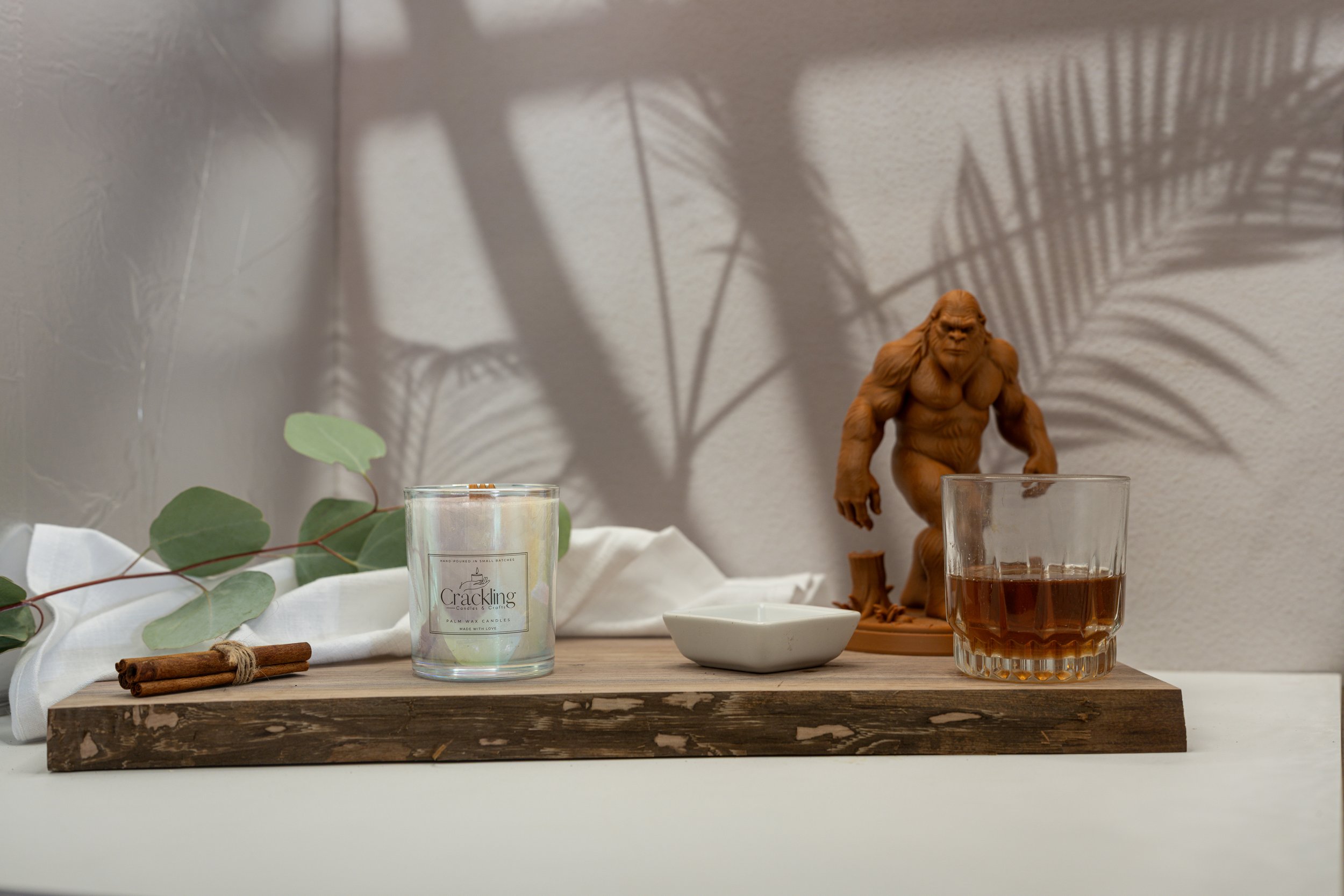 Indian Sandalwood palm wax candle styled with a Bigfoot figurine, neutral linen, and warm wood