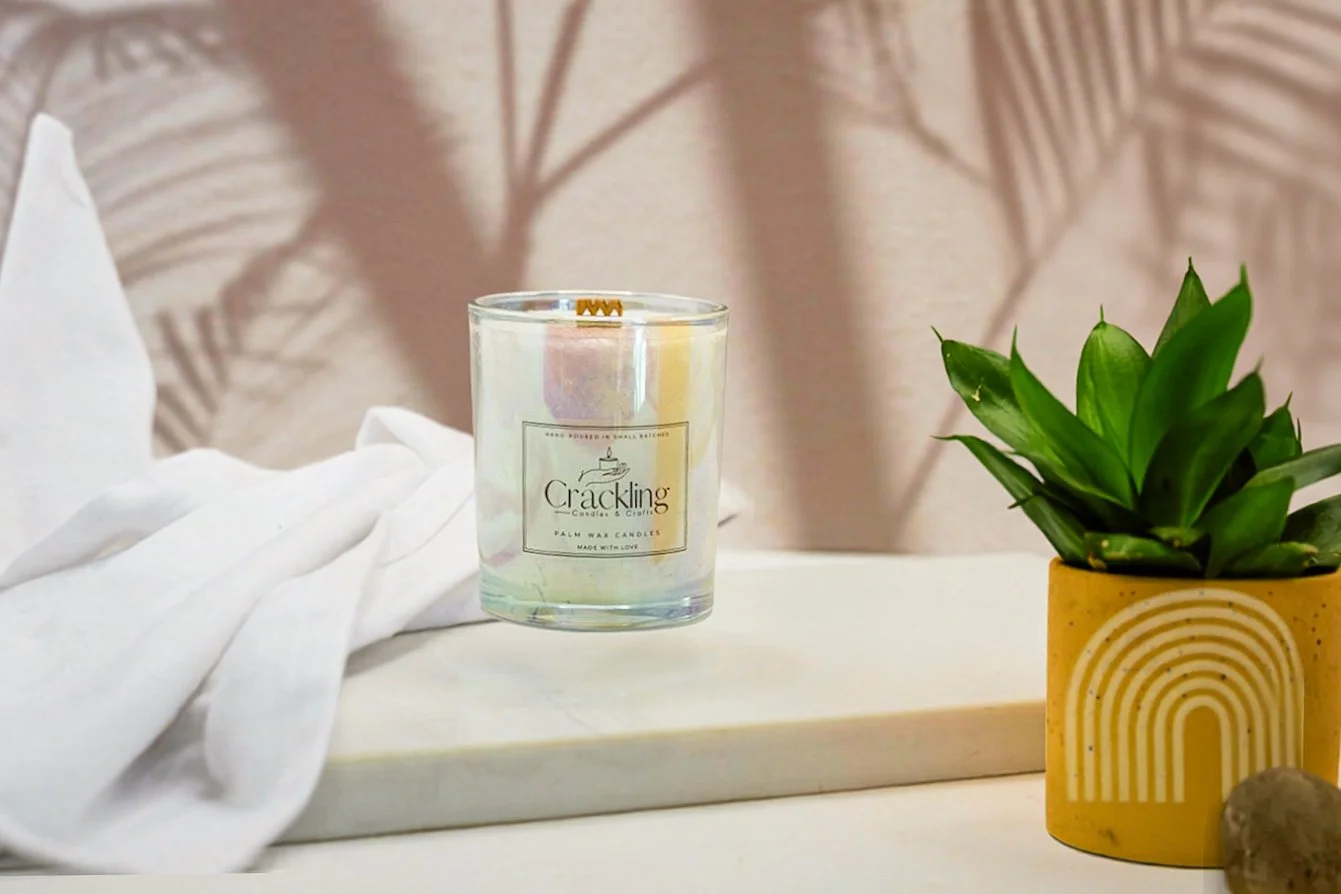 6 oz Agave palm wax candle with a wooden wick, styled on a white riser with a green plant and soft neutral linen.