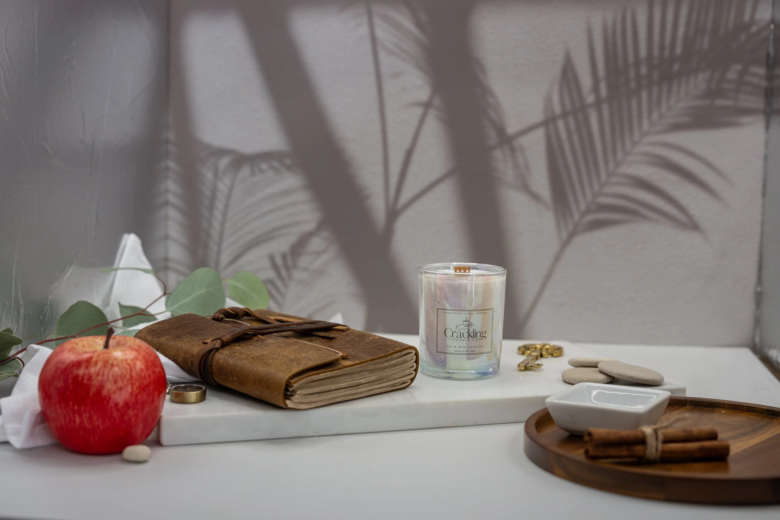 6 oz Apple Jazz palm wax candle with a wooden wick, styled with a red apple, a leather journal, and soft greenery.