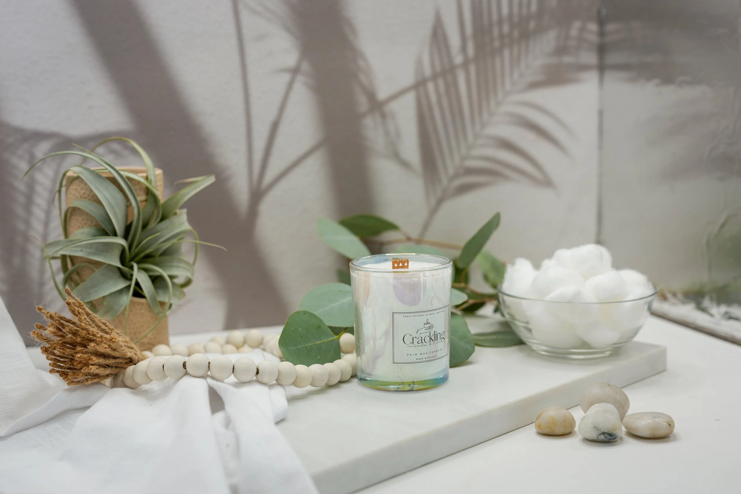 Baby Powder candle displayed with a succulent, eucalyptus leaves, white cotton, and natural beads in a calming neutral setting.