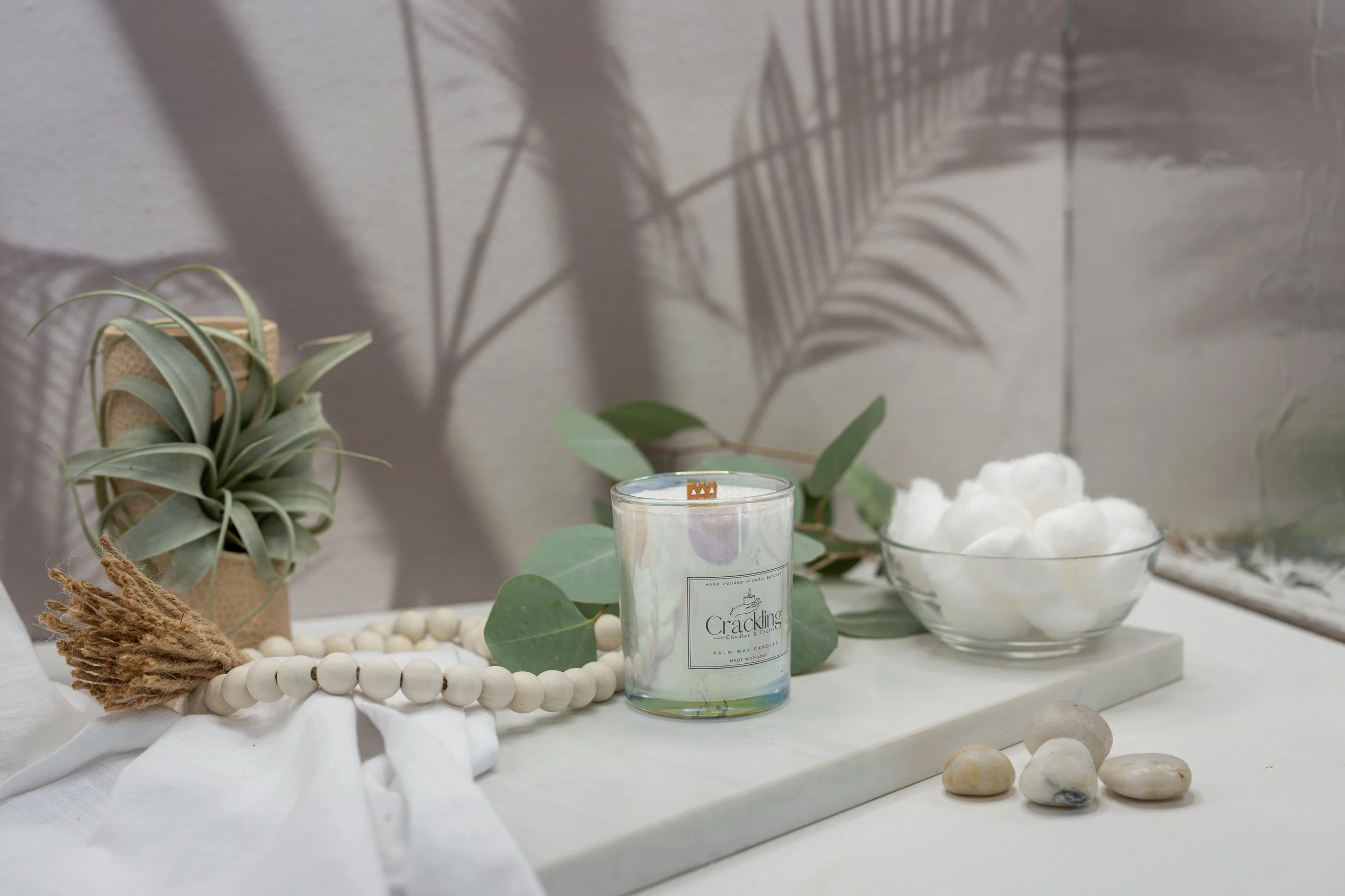 Hand-poured Baby Powder candle with a wooden wick, styled between soft greenery and a bowl of white cotton.