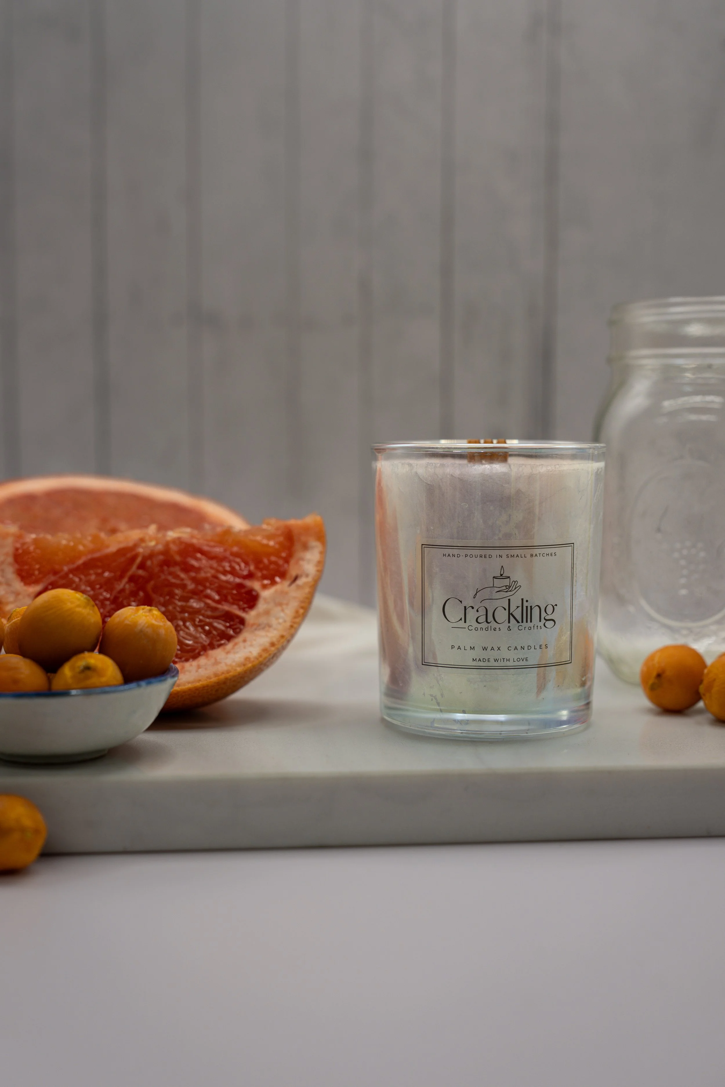 Front view of the Grapefruit & Kumquat candle styled with grapefruit, kumquats, and a neutral backdrop.