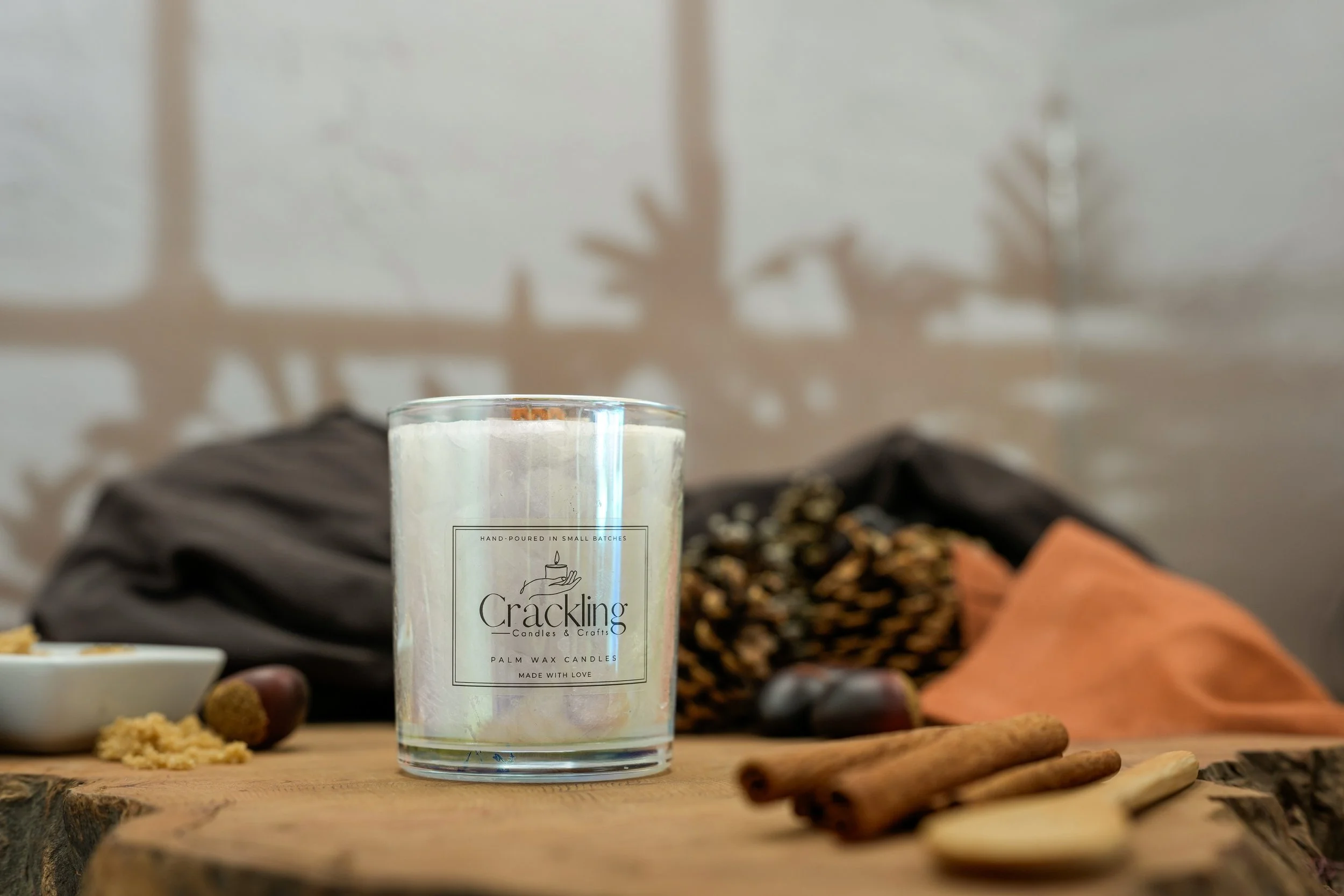 Close-up of a Chestnuts & Brown Sugar candle styled with pinecones, cinnamon sticks, chestnuts, and rustic wood.
