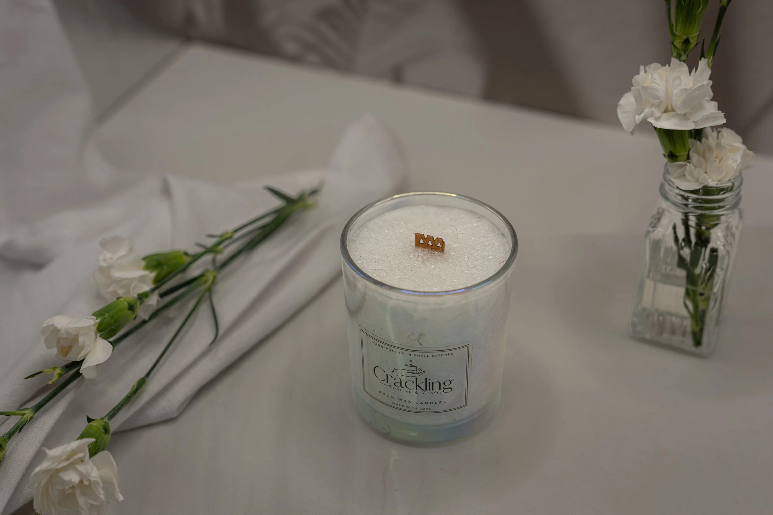 Top view of a Victorian Rose palm wax candle with a wooden wick, styled with white flowers