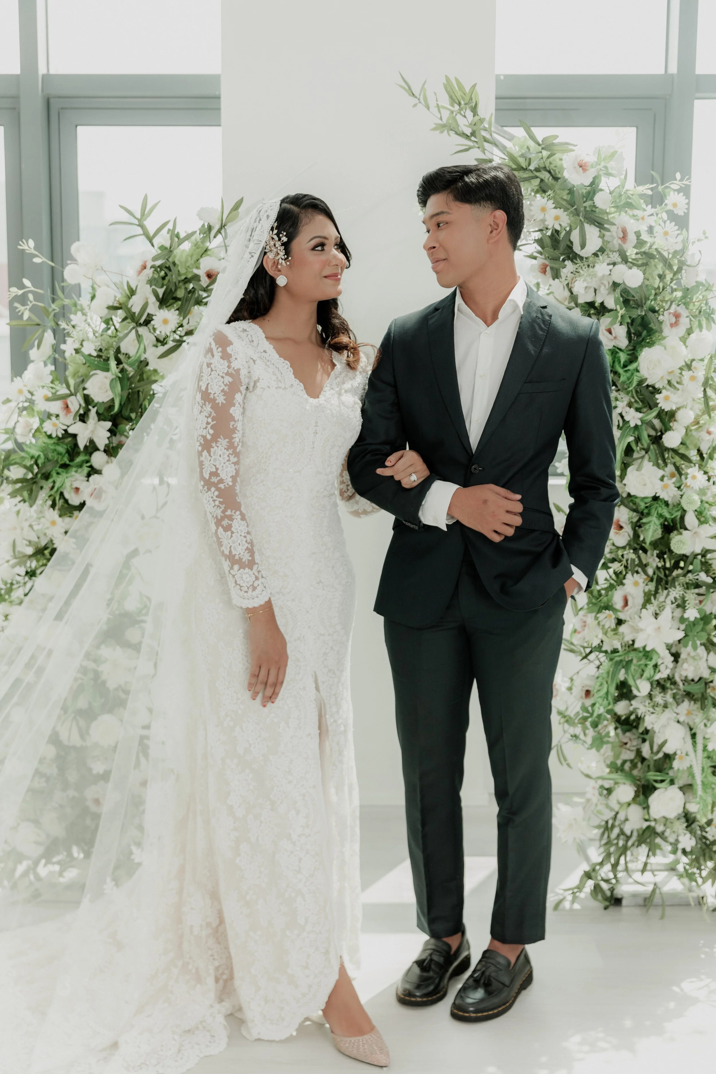 asian couple with wedding floral arch in the background