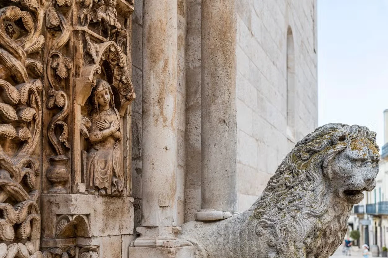 Statue di pietra di un leone e una decorazione scolpita di un personaggio femminile con un giardino di elementi naturali
