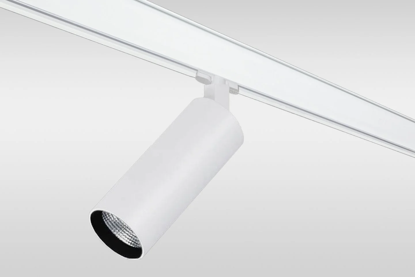 Close-up of a white track lighting fixture with a cylindrical spotlight, mounted on a ceiling