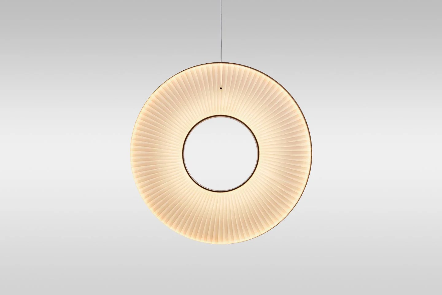 Circular pendant light with pleated beige shade hanging from the ceiling