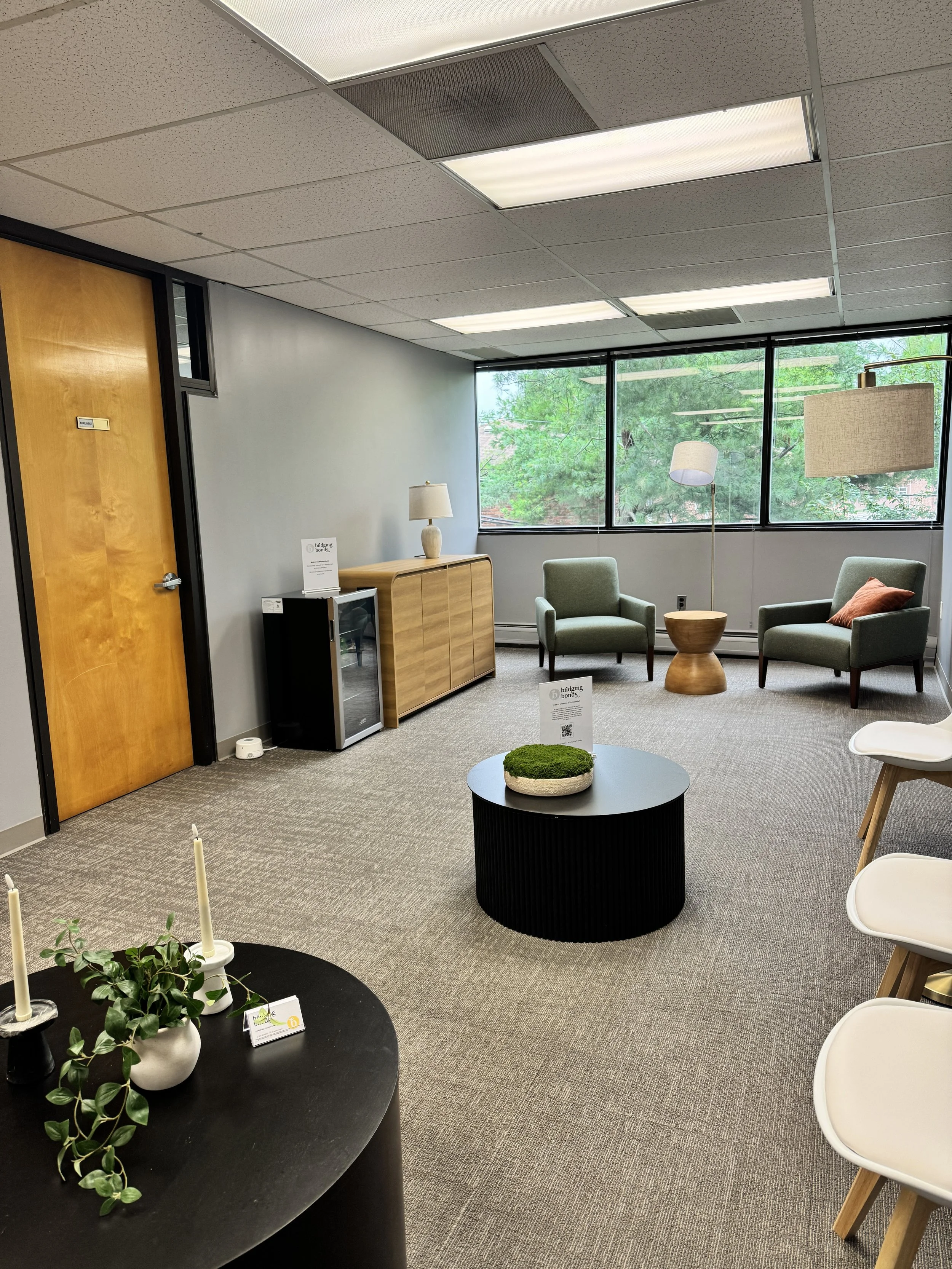 Waiting area at the Parsippany, NJ therapy office with green armchairs, a beverage fridge, and a large window