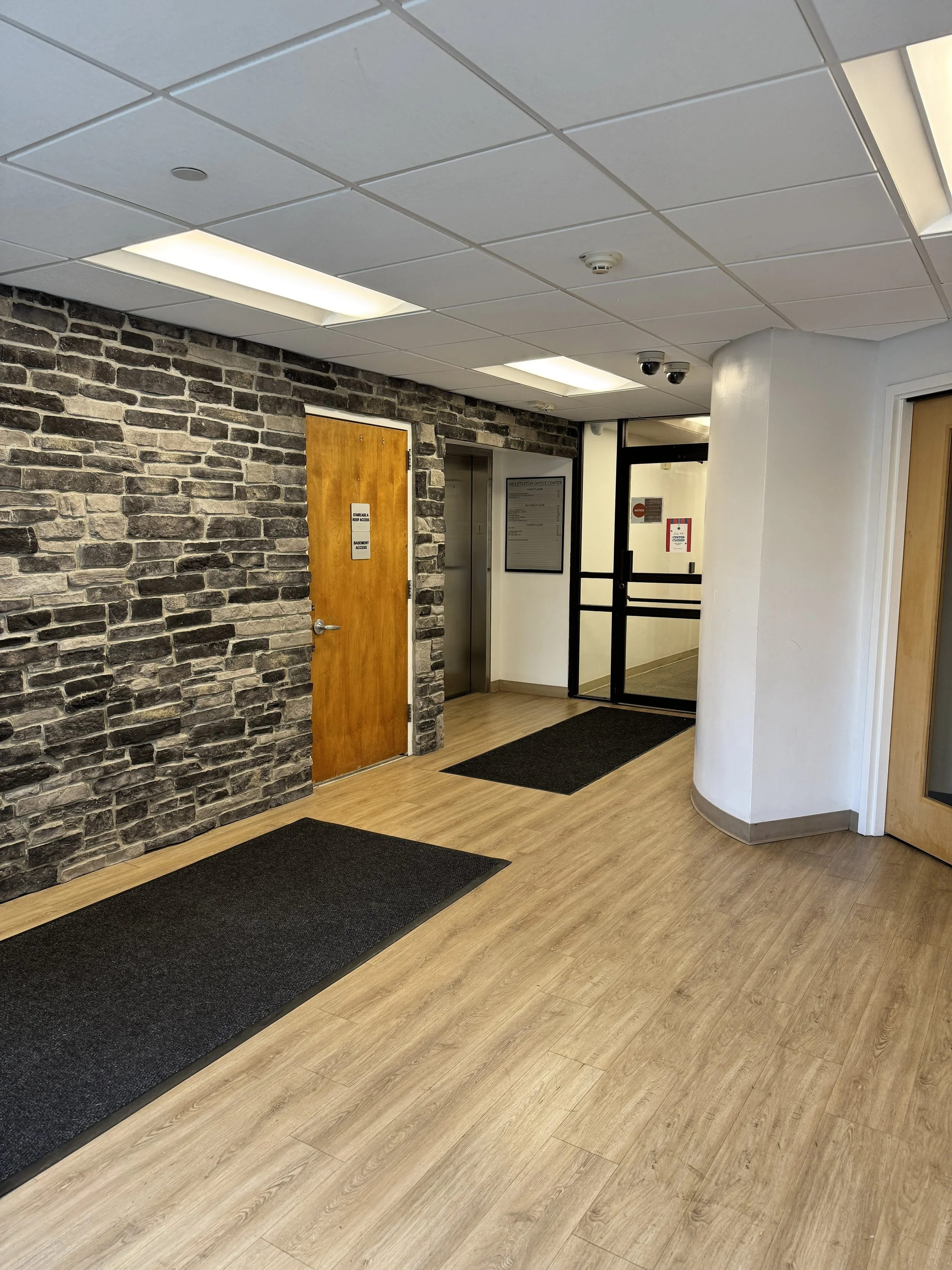 Lobby entrance at 160 Littleton Rd in Parsippany, NJ, with a stone accent wall and wood door leading to the elevators