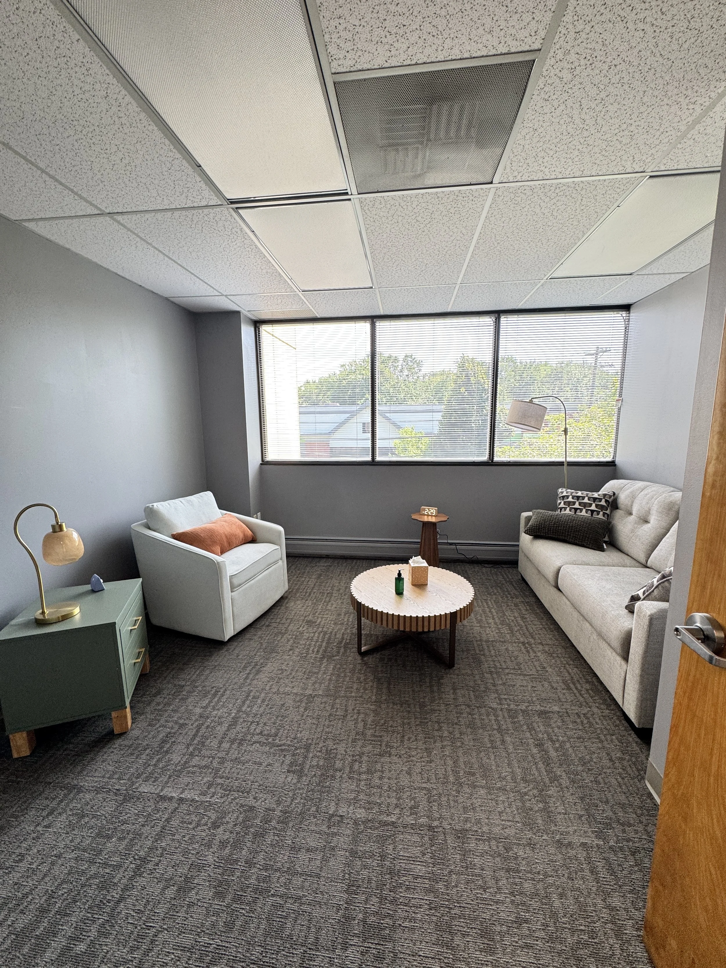 Private therapy room in Parsippany, NJ with a sofa, armchair, and wide windows