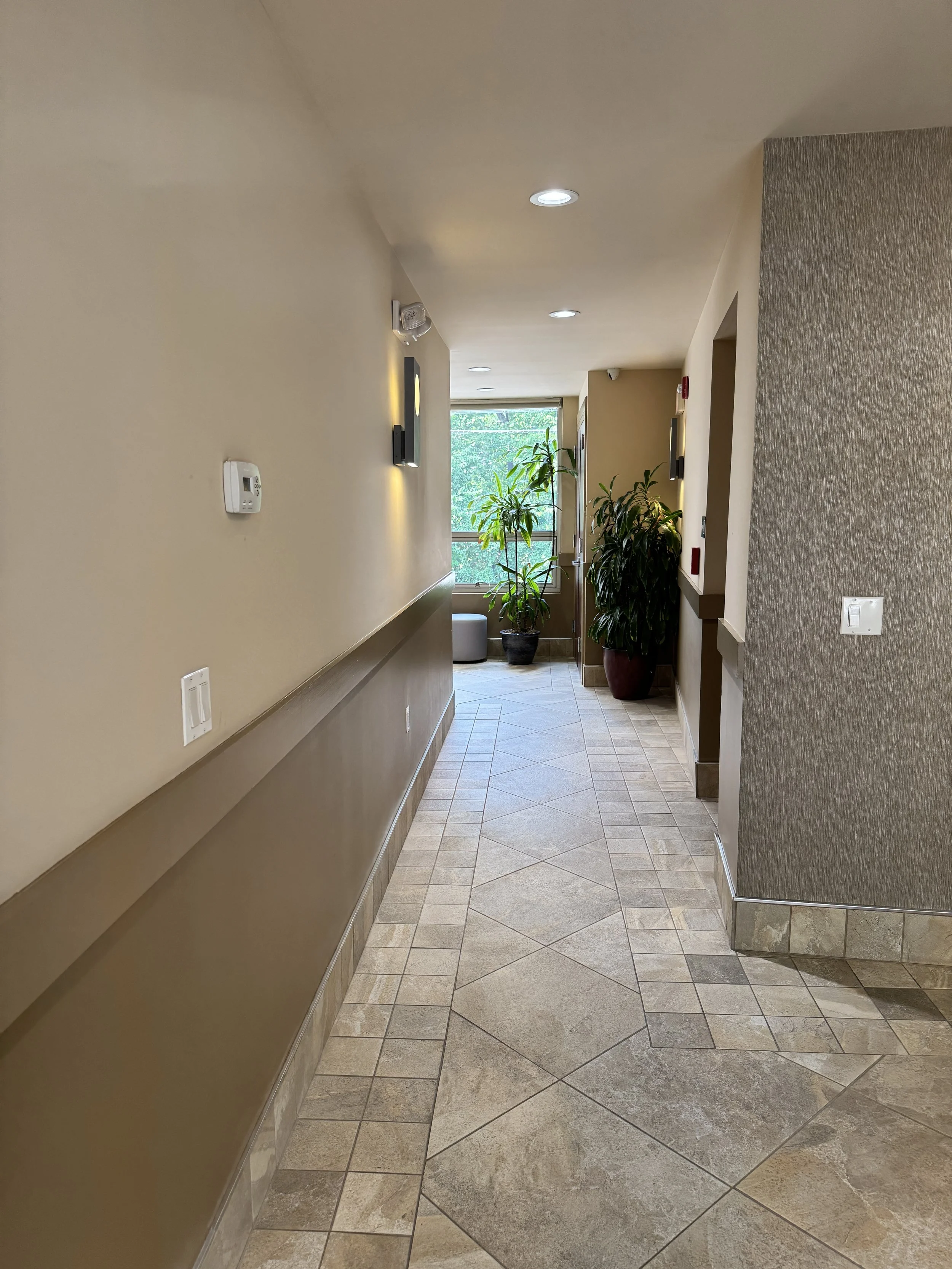 When the elevator doors open on the second floor, turn to your left. Head down the tiled hallway past the indoor plants toward the suite entrance, where you'll walk towards our serene shared waiting space.