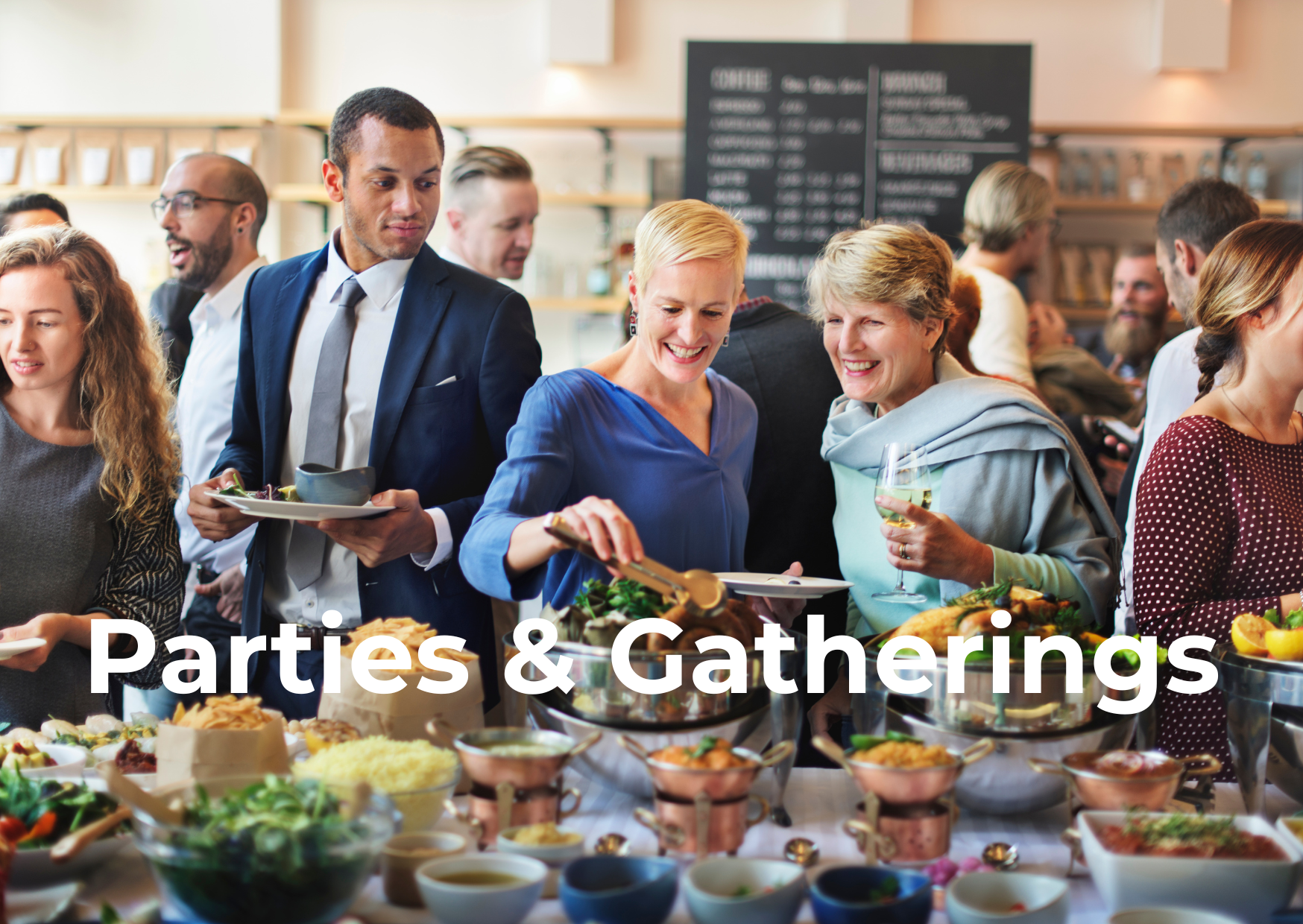 People gather around a buffet table with various dishes at a party or event, with a menu board visible in the background.