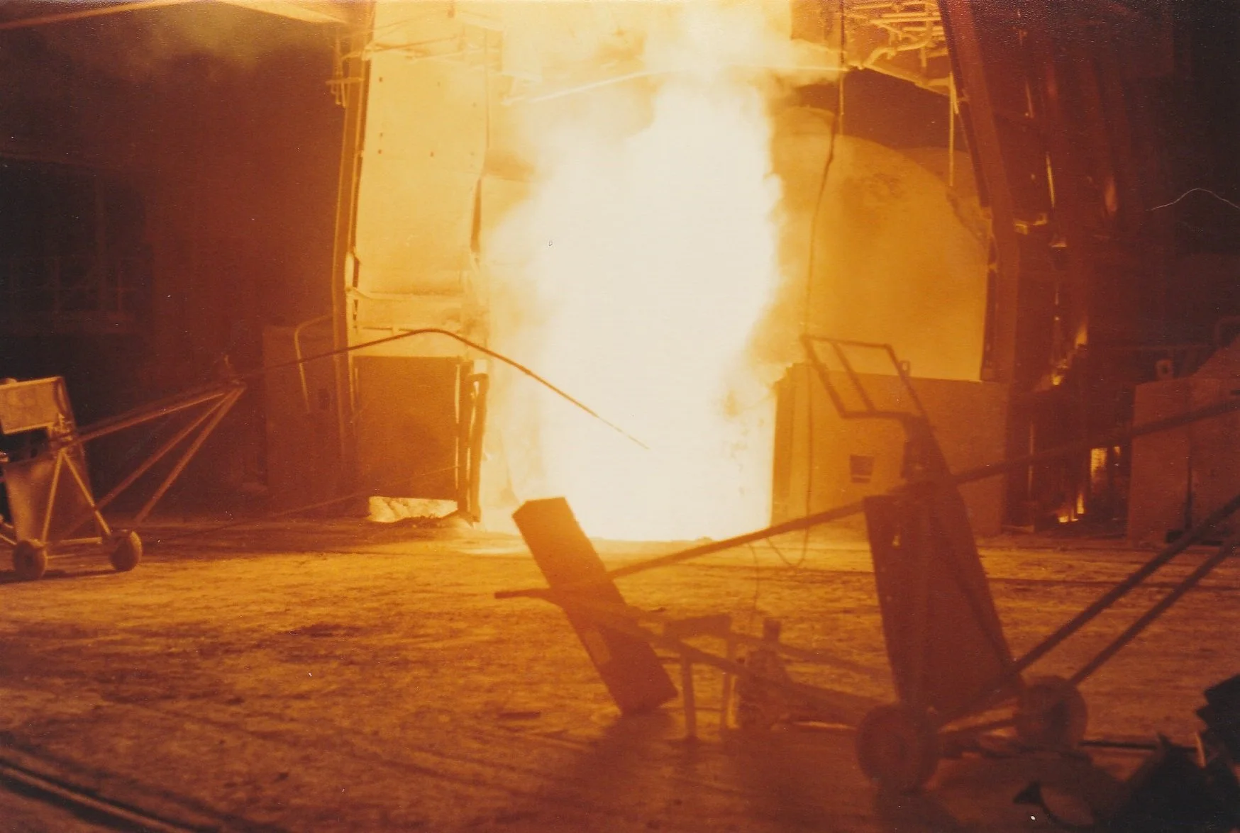 An oxygen steelmaking plant furnace pouring melted steel into a ladle