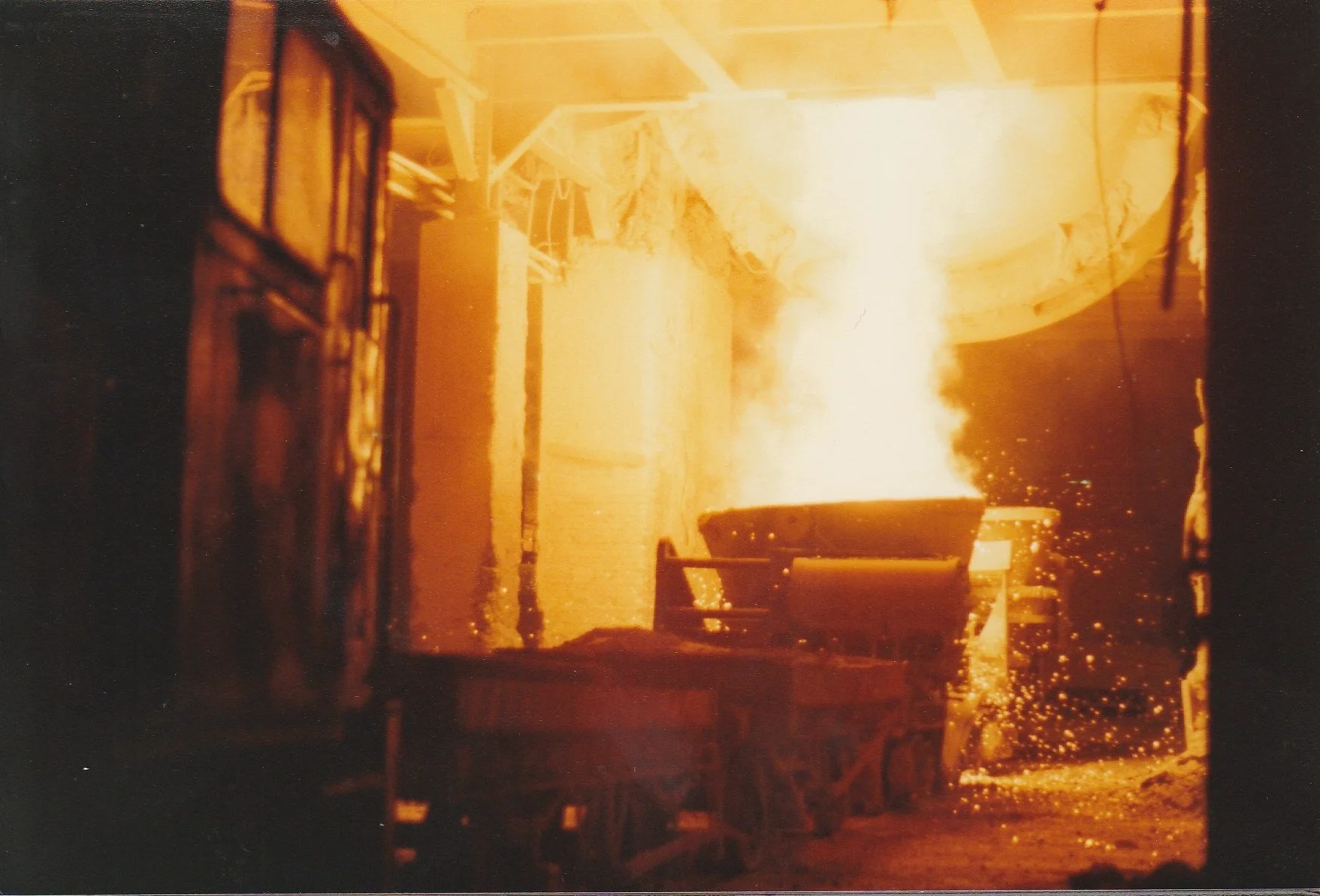 An oxygen steelmaking plant furnace pouring melted steel into a ladle