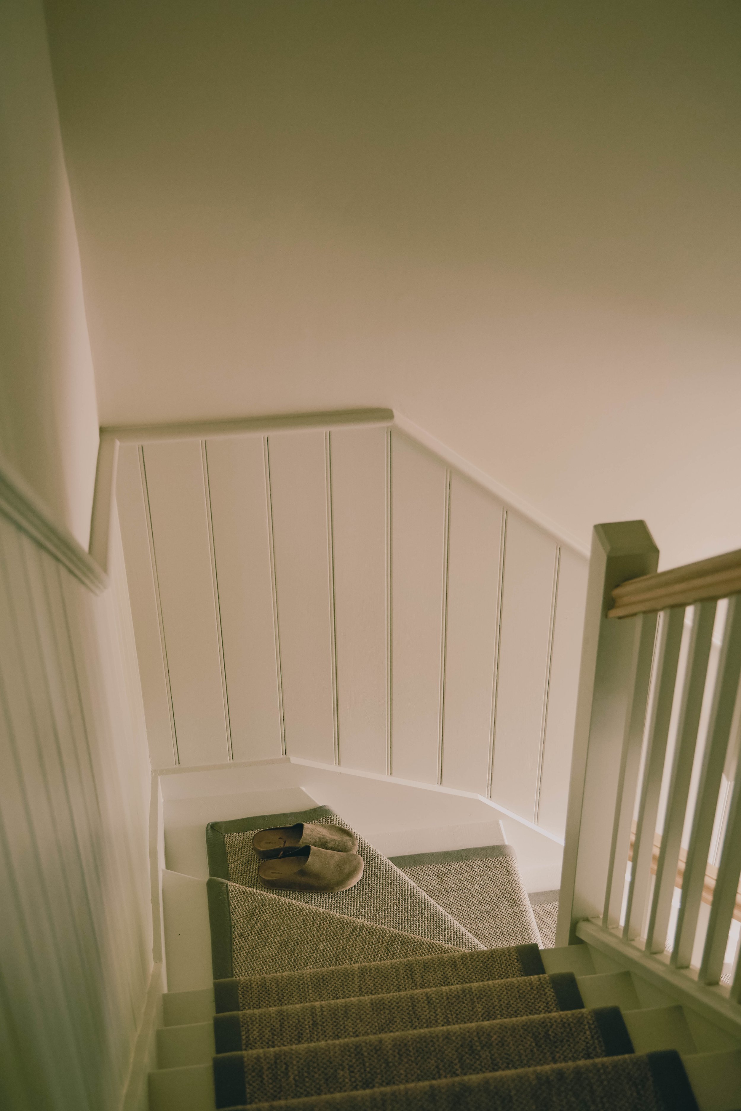 Carpeted staircase with tongue and groove panelled walls