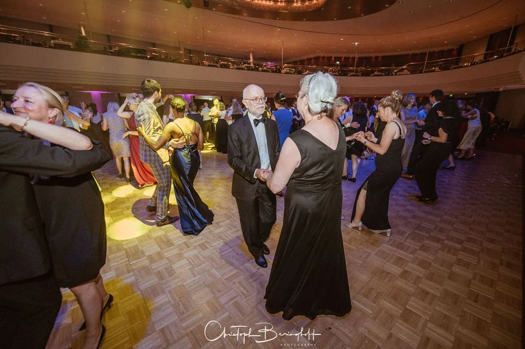 Menschen tanzen mit formeller Kleidung in einer eleganten Veranstaltungshalle