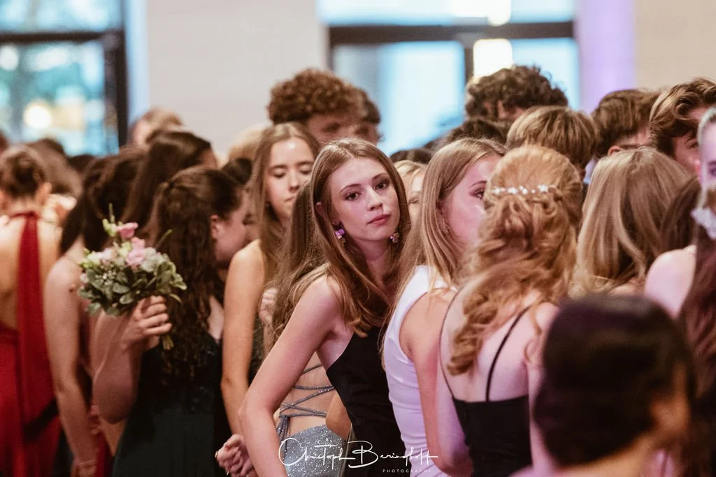 Eine Gruppe junger Frauen in formeller Kleidung, vermutlich bei einer Feier oder einem Event, mit Blumen und Schmuck.