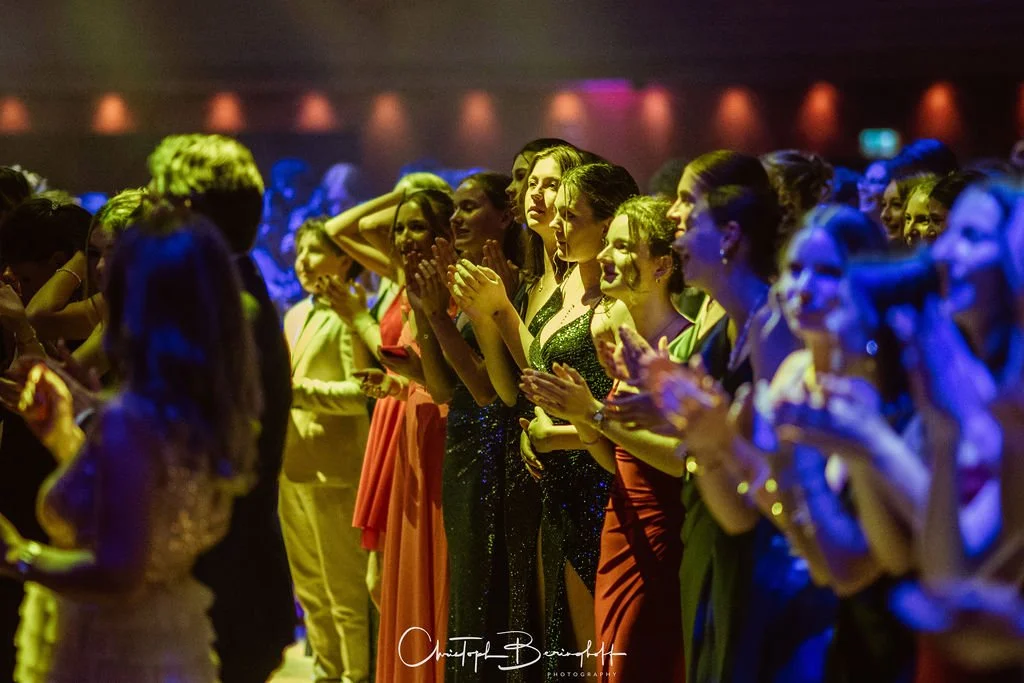 Menschen bei einer Feier oder Gala, die in eleganter Kleidung stehen und Applaus spenden.
