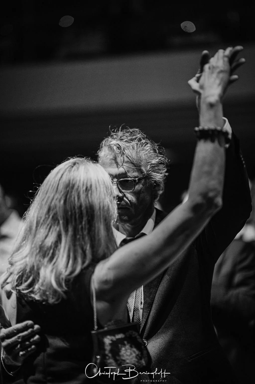 zwei Menschen tanzen eng umschlungen, schwarzer und weißer Ton, ein Mann mit Brille und grauem Haar, eine Frau mit blonden Haaren, bei einer Party oder Feier