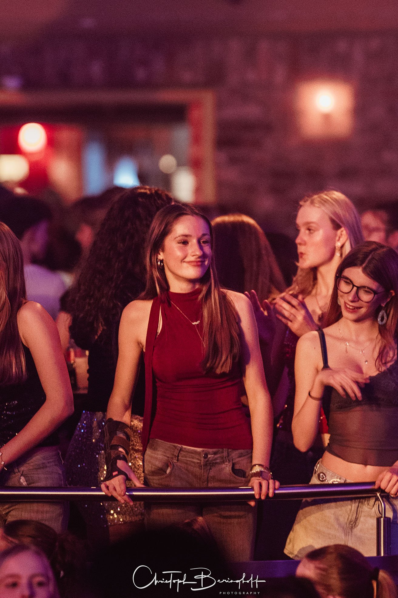 Junge Frauen tanzen und feiern auf einer Party in einer Bar oder einem Club, beleuchtet mit bunten Lichtern.