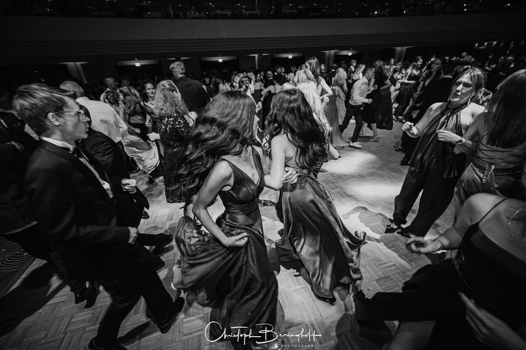 Menschen tanzen auf einer Party oder einem Ball im Abendkleid und Anzügen, Schwarz-Weiß-Fotografie.