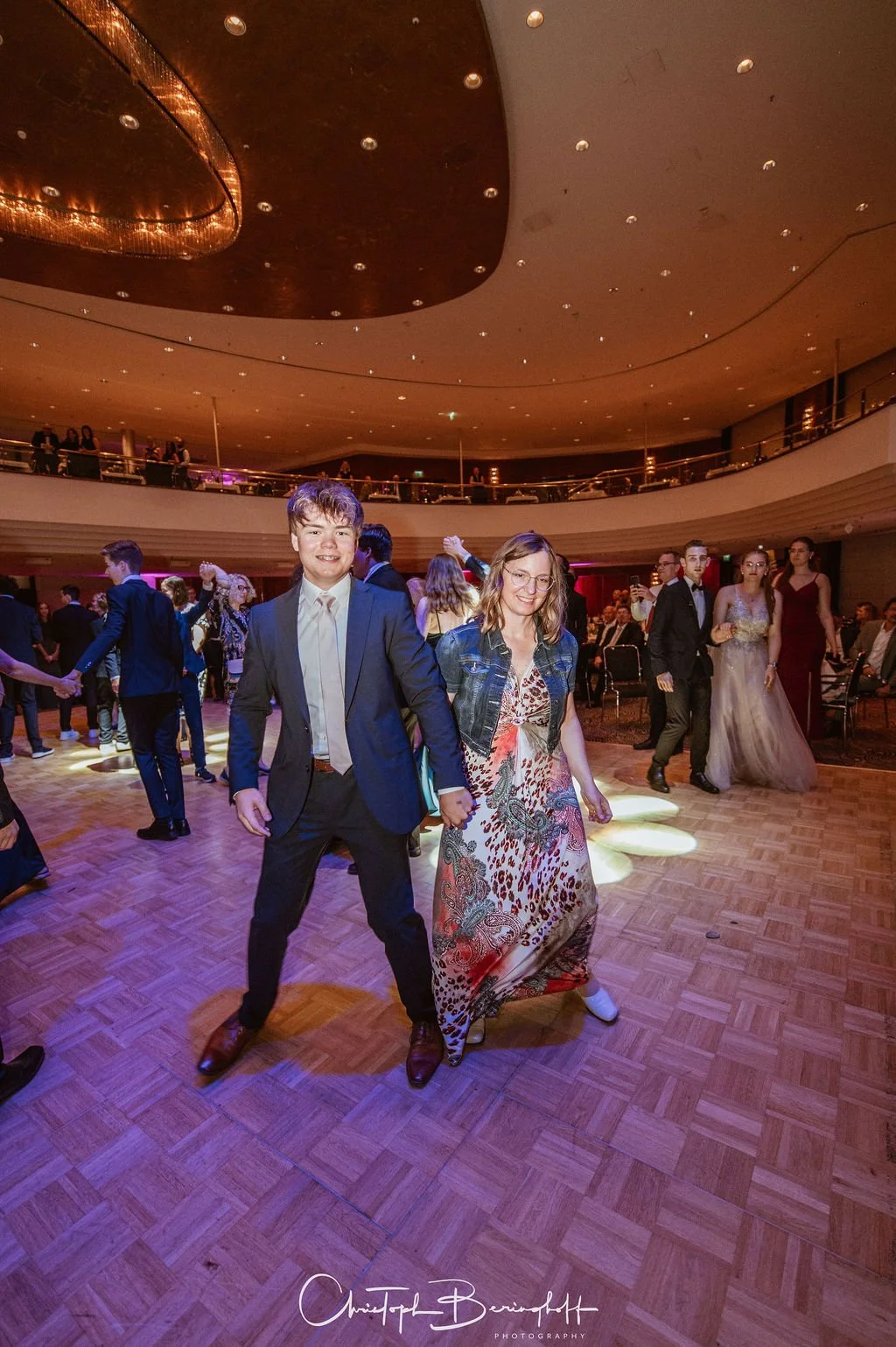 Menschen tanzen in einem festlichen Saal bei einer Feier oder einem Ball.