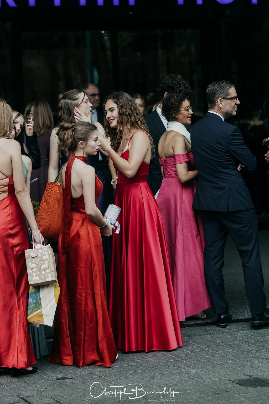 Gruppe von Menschen in eleganten Abendkleidern und Anzügen bei einer Veranstaltung, die sich unterhält.