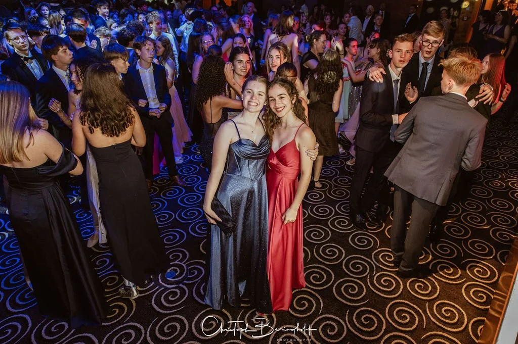 Junge Menschen in eleganten Abendkleidern und Anzügen tanzen und feiern bei einer Party oder einem Ball im festlichen Ambiente.