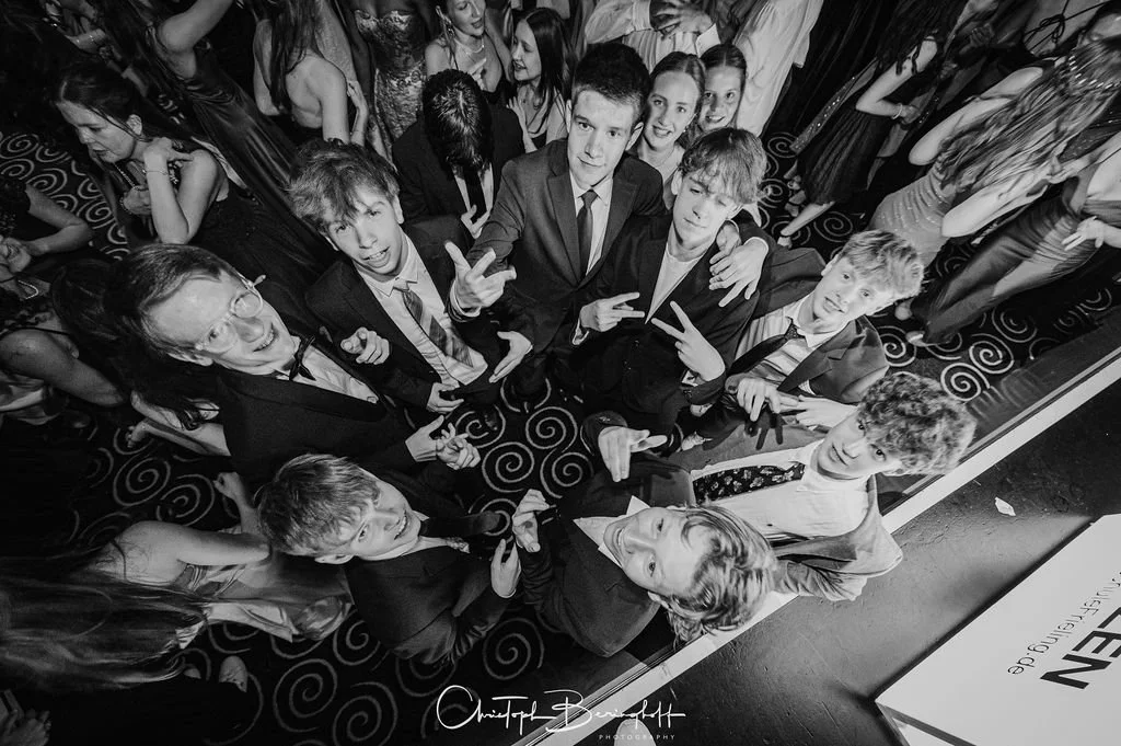 Gruppe von Jugendlichen und Kindern, die auf einer Party gekleidet sind, pose für ein Foto, einige zeigen Fingergesten, alle lachen und haben Spaß.