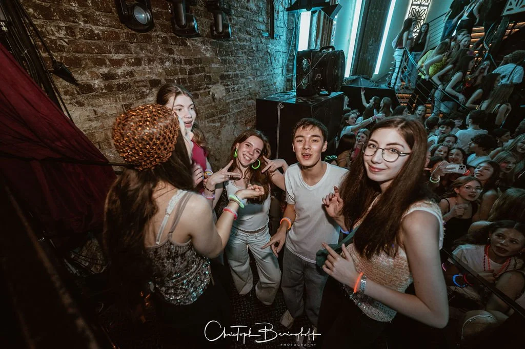 Teenagers are partying at a club, dancing and listening to music.