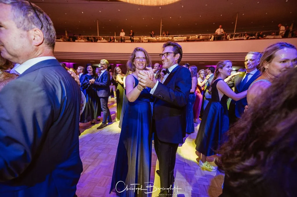 Menschen tanzen auf einer festlichen Veranstaltung im eleganten Rahmen, mit leuchtenden Farben und vergnügter Atmosphäre.